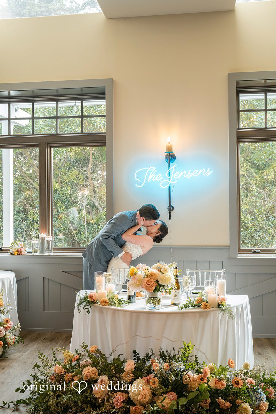 Daniel + Karen A bride and groom leaning over a heavily decorated floral head table.
