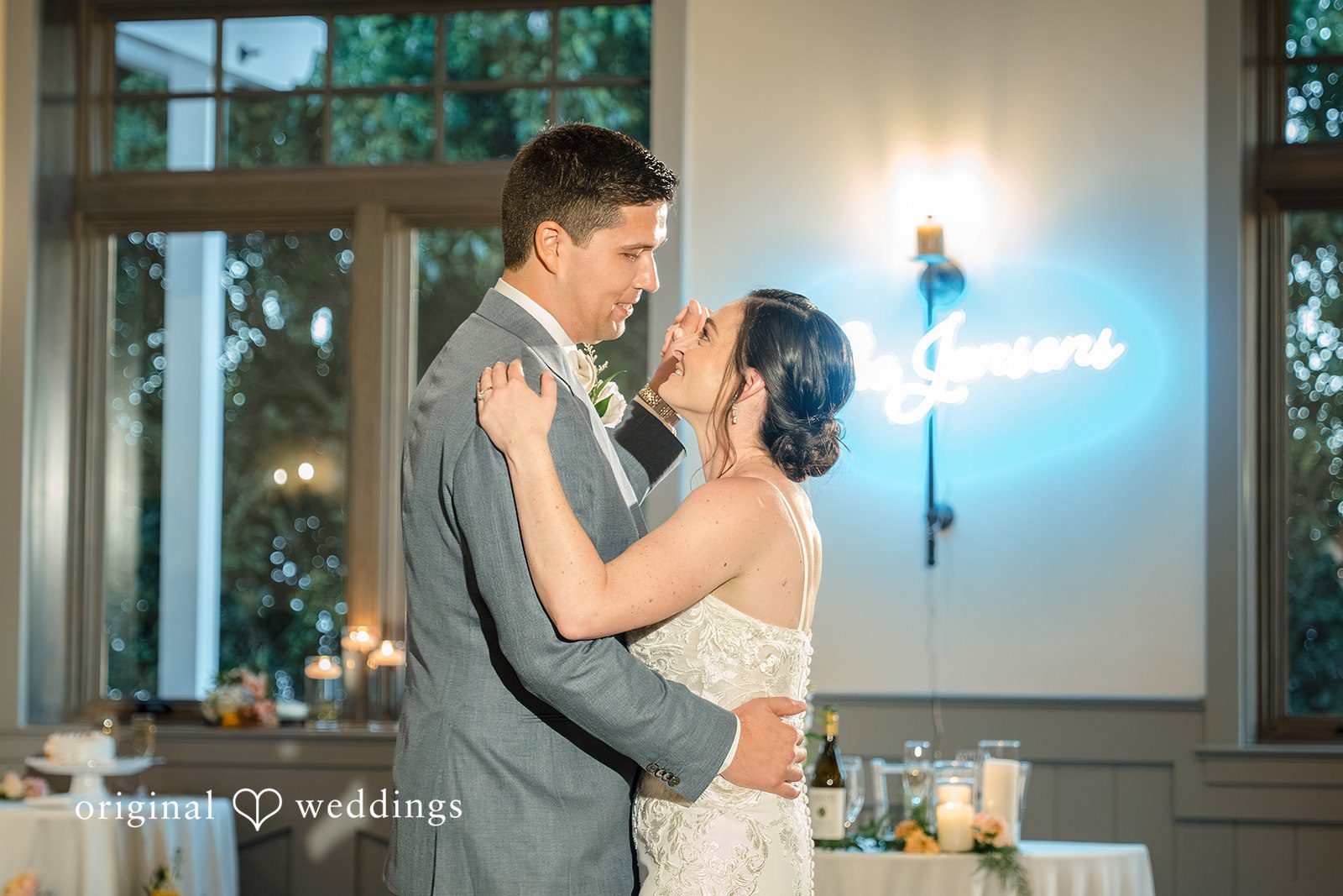 Daniel + Karen A bride and groom sharing a moment next to a glowing neon sign.