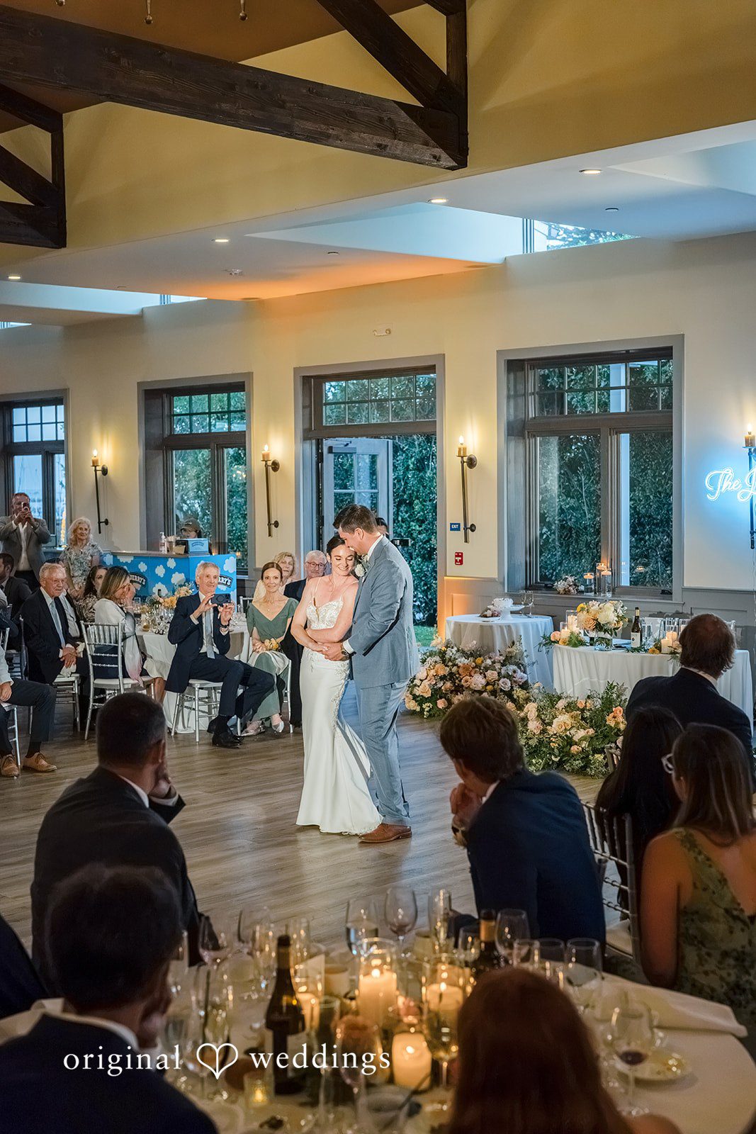 Daniel + Karen A view of a wedding reception dance floor filled with guests under warm lighting.