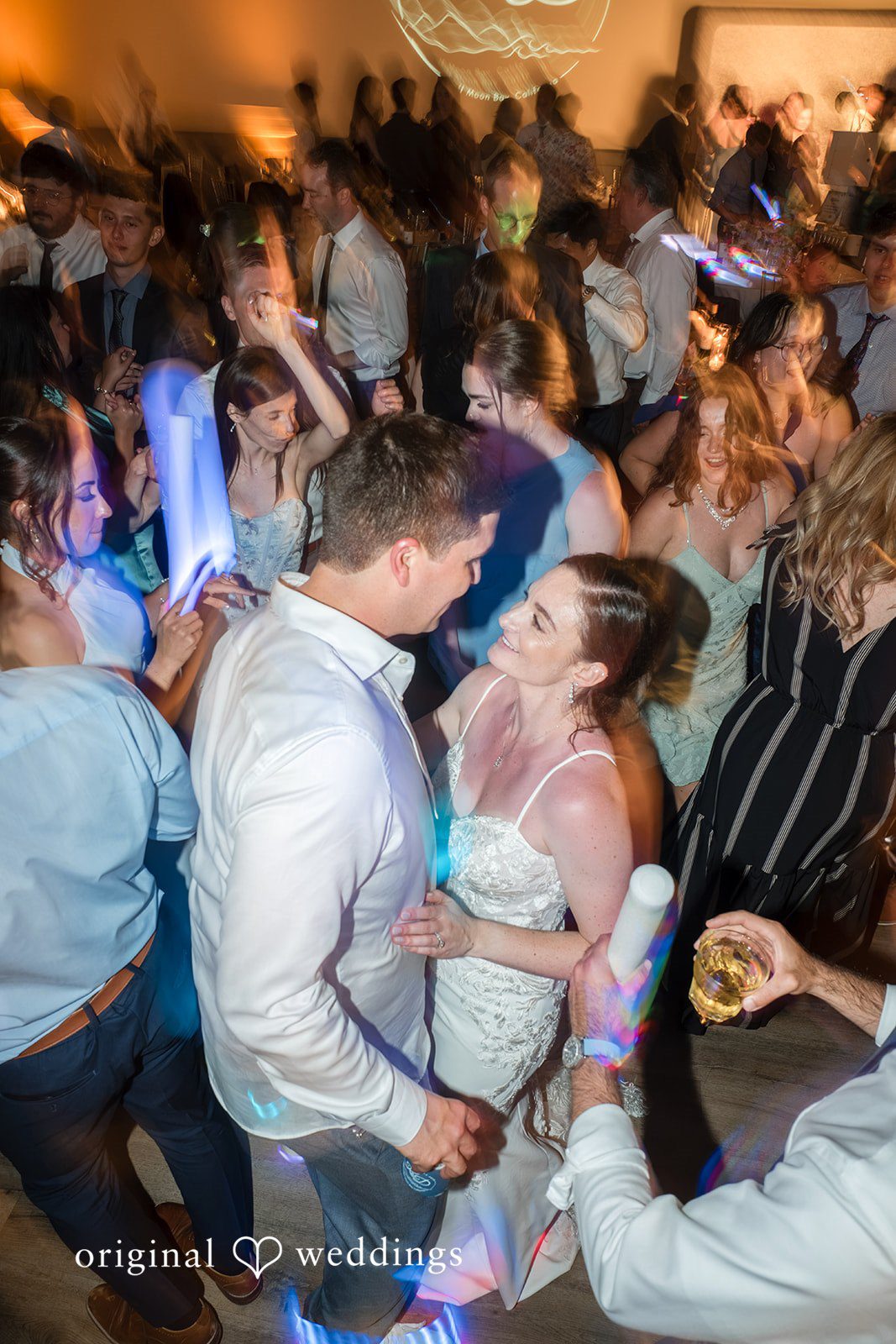 Daniel + Karen A crowded dance floor filled with wedding guests celebrating at night.