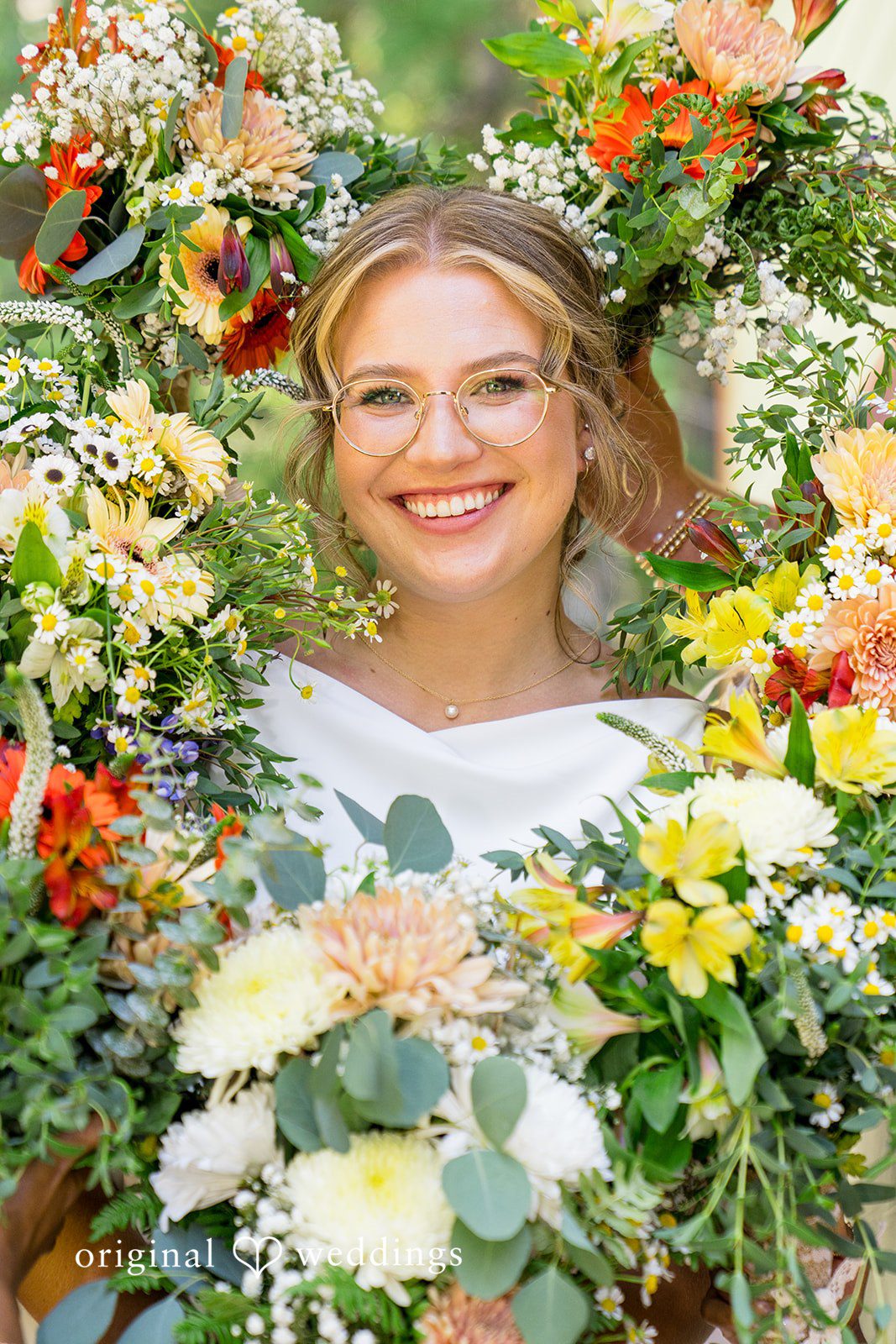 Abigail + Reece A bride smiling through a vibrant floral wreath frame.