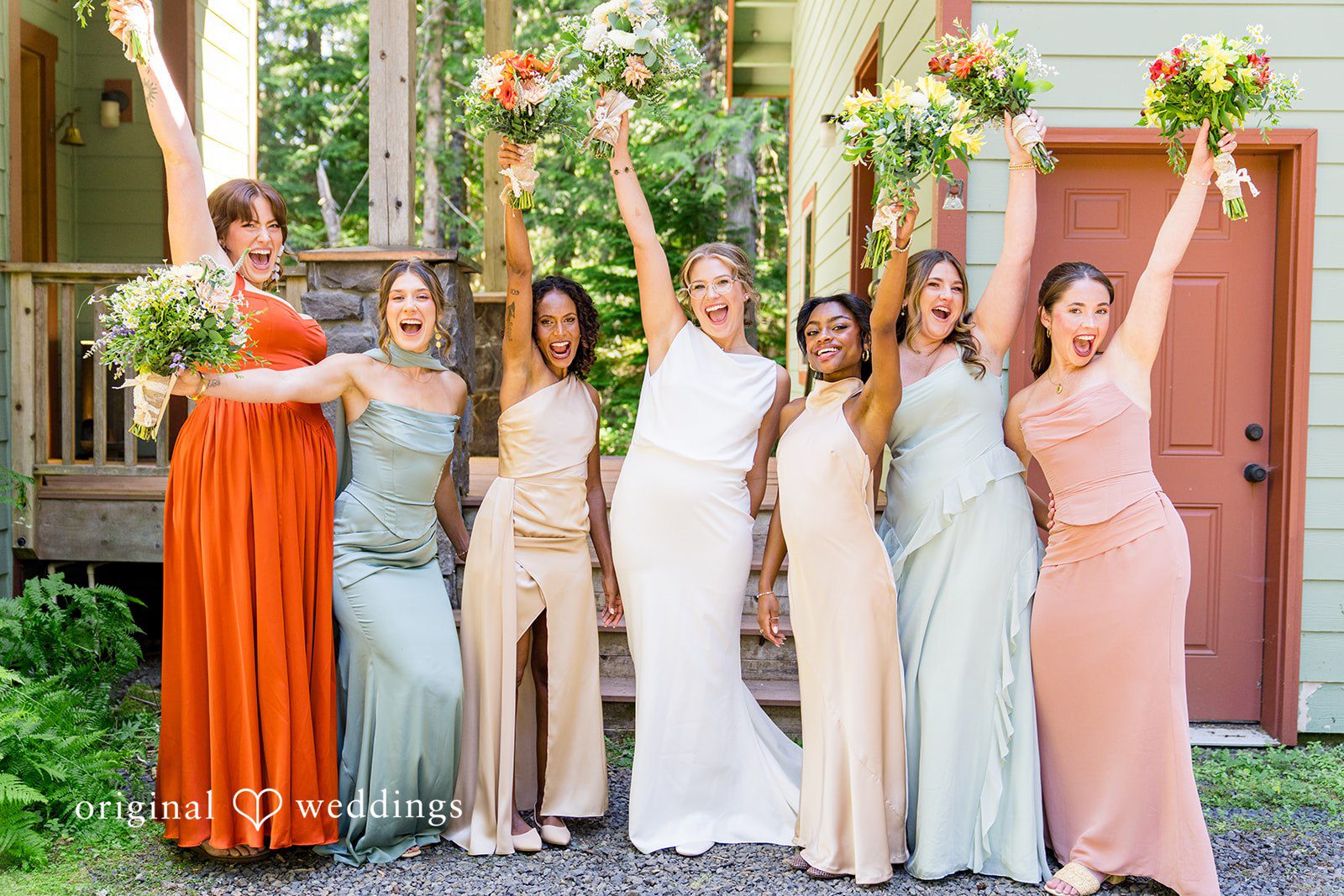 Abigail + Reece A bridal party in multi-colored dresses holding up their bouquets.