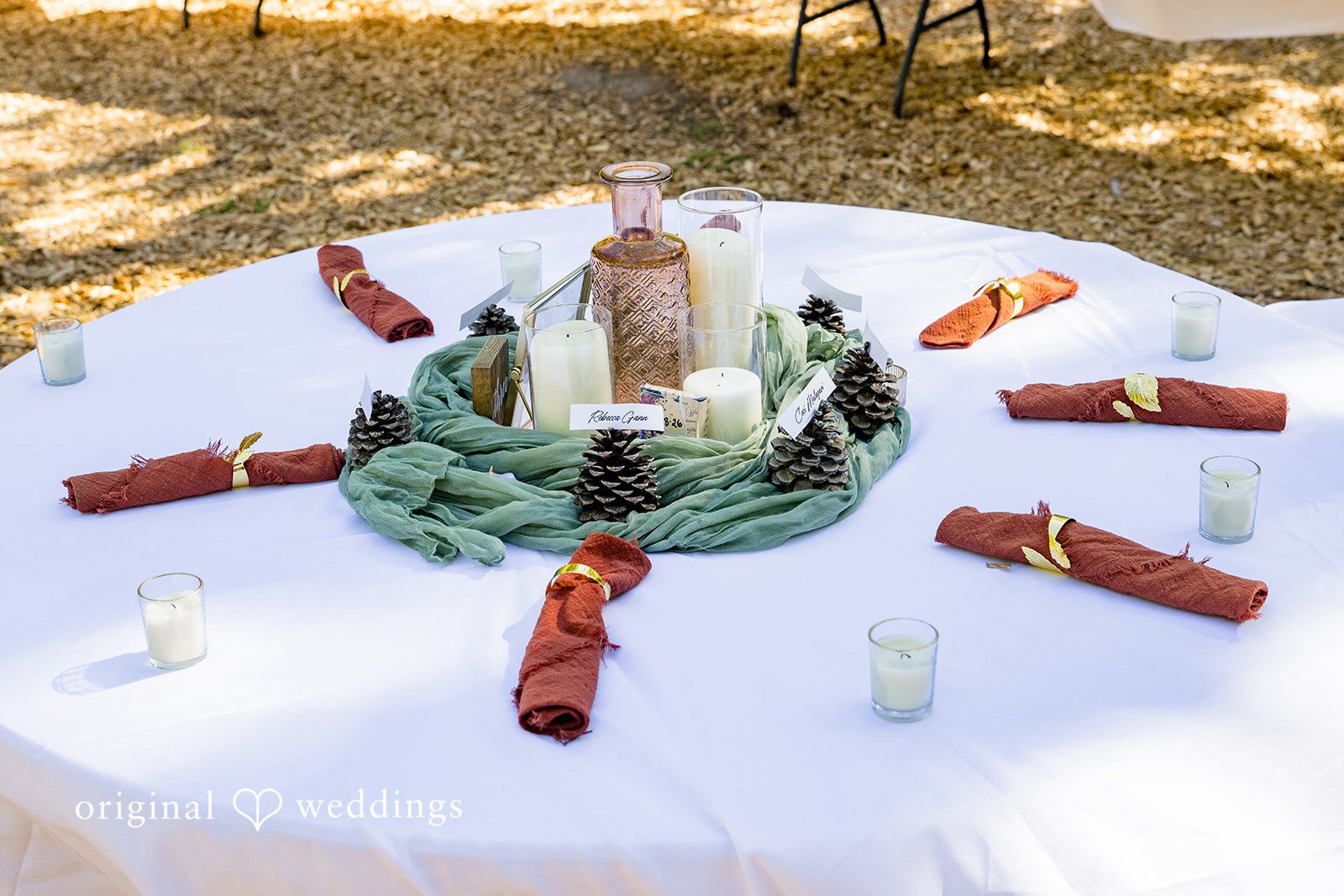 Abigail + Reece A round table set with green linens and rustic centerpieces.