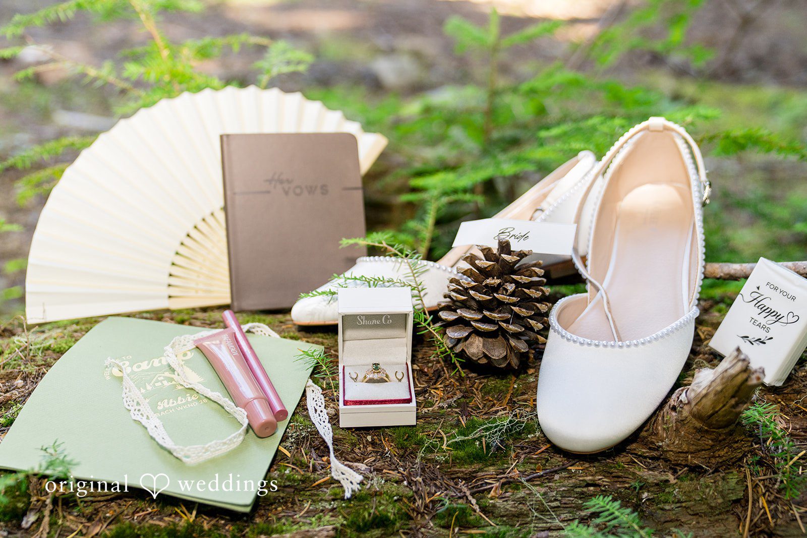 Abigail + Reece Bridal accessories including shoes, stationery, and small decorative items arranged on the ground.