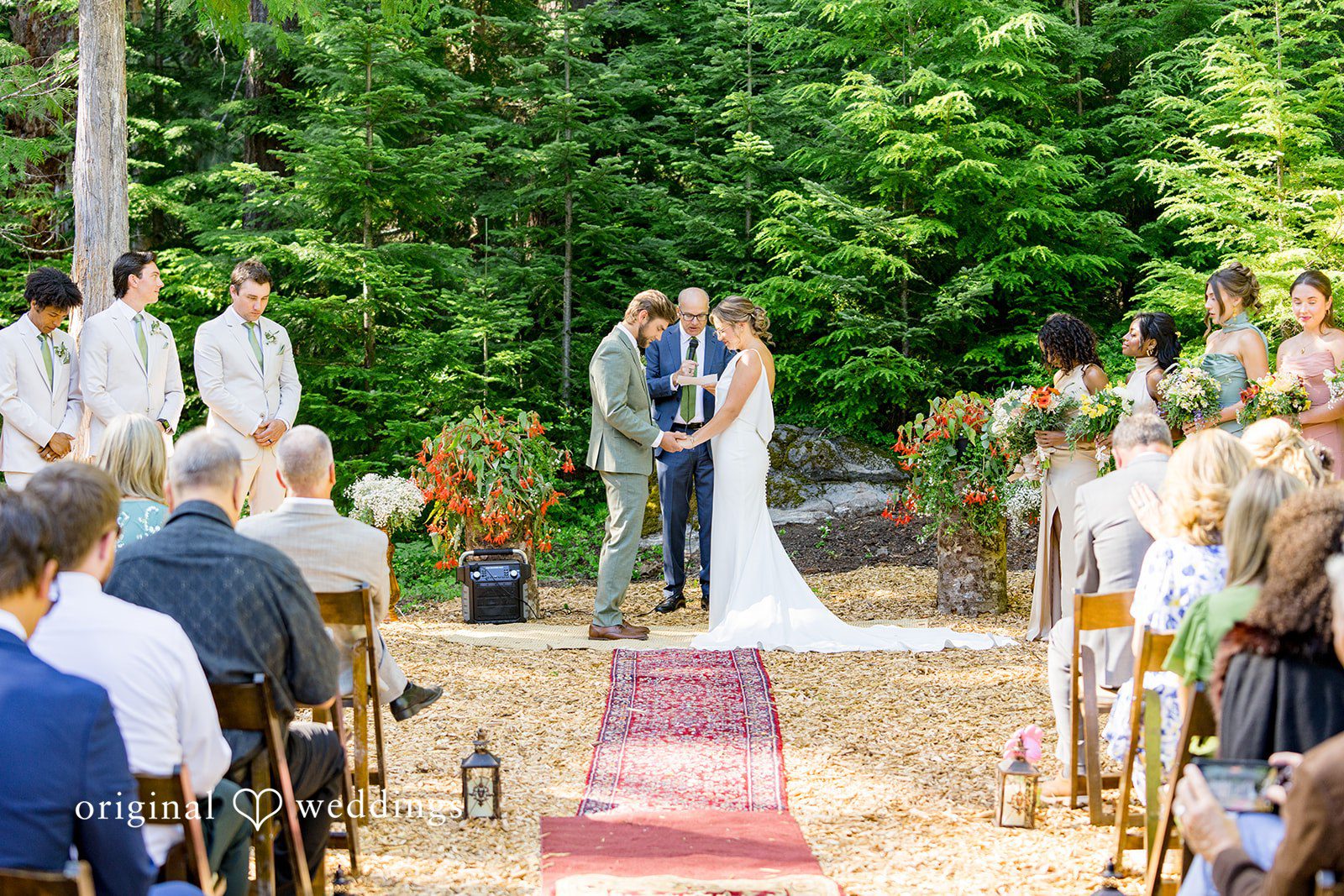 Abigail + Reece A wedding processional walking down a red aisle runner.