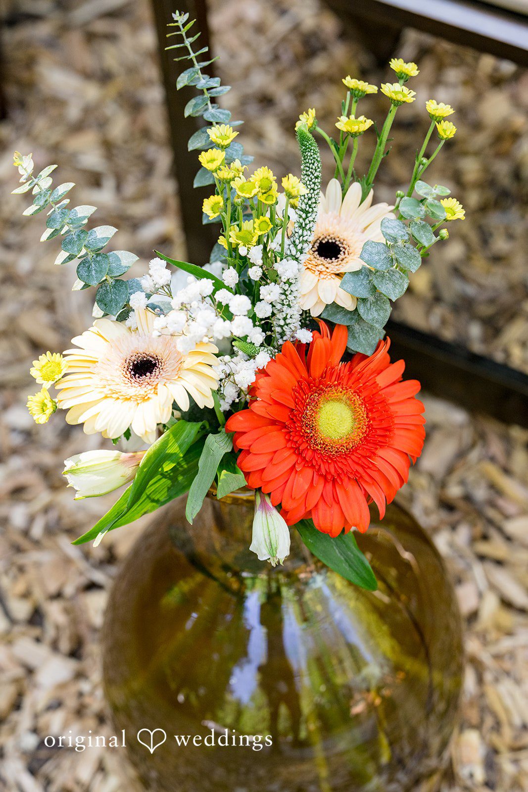 Abigail + Reece A floral arrangement with a prominent orange gerbera daisy in a glass vase.