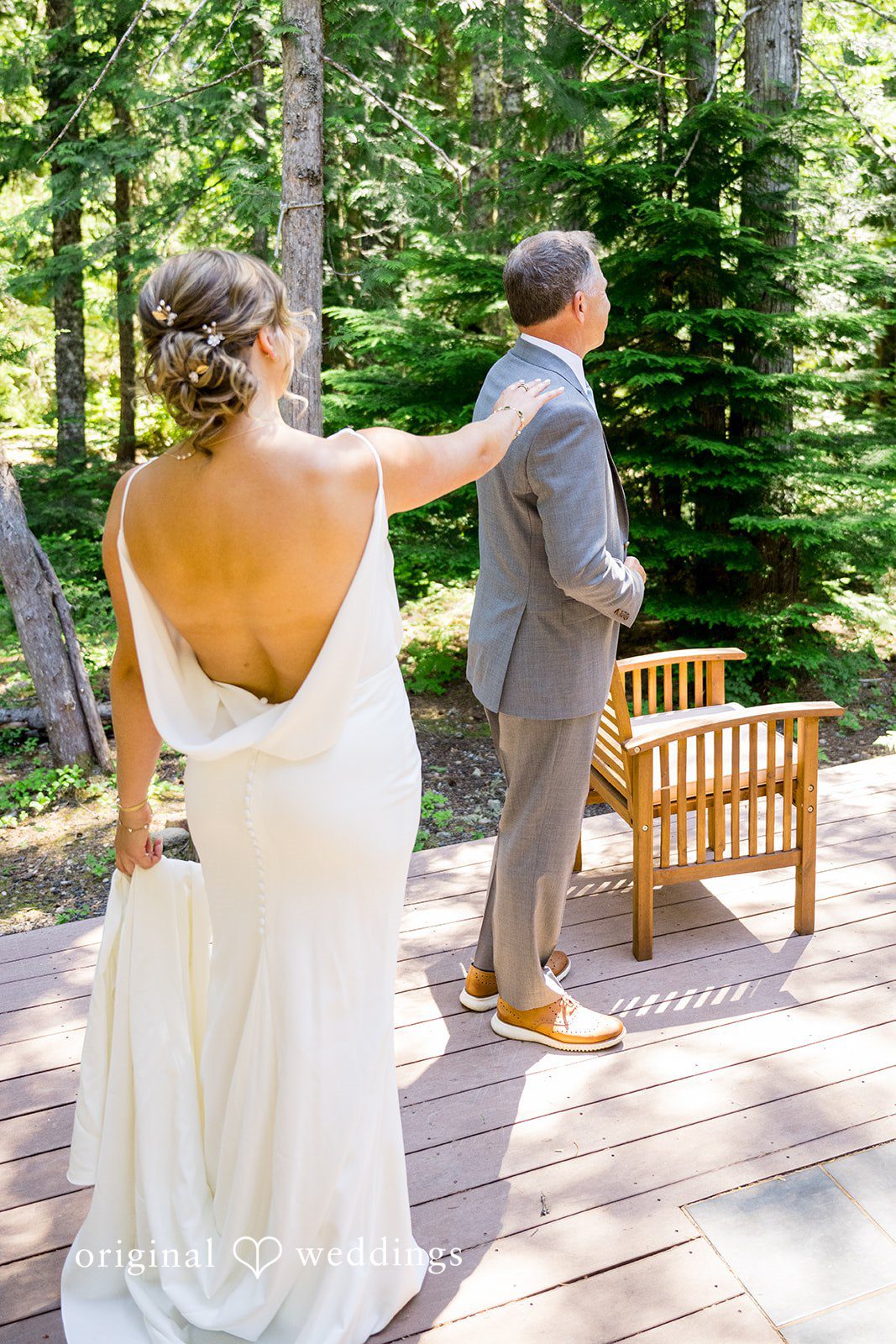 Abigail + Reece A bride in a backless dress standing near wooden chairs.