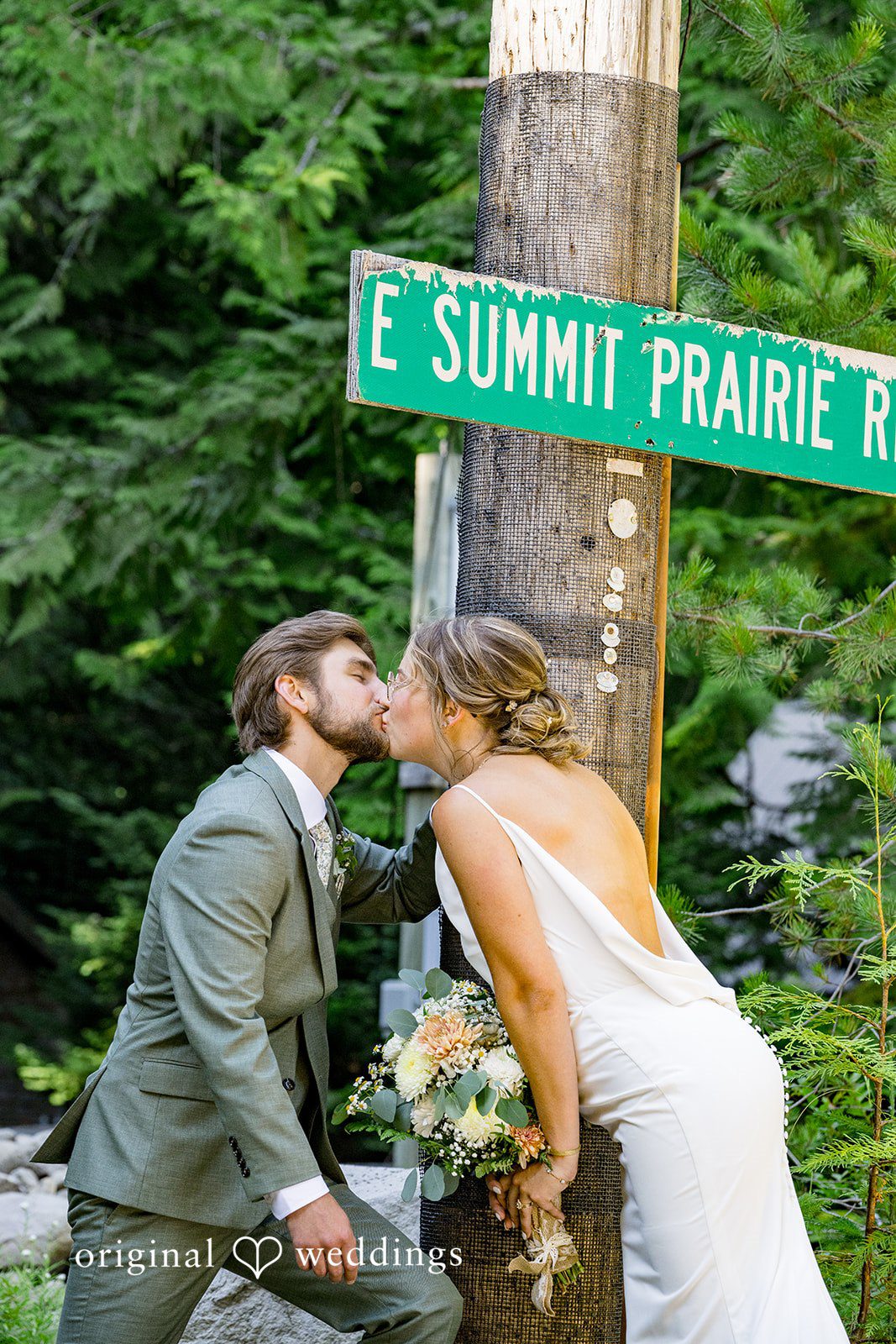 Abigail + Reece A bride and groom kissing next to a green street sign.