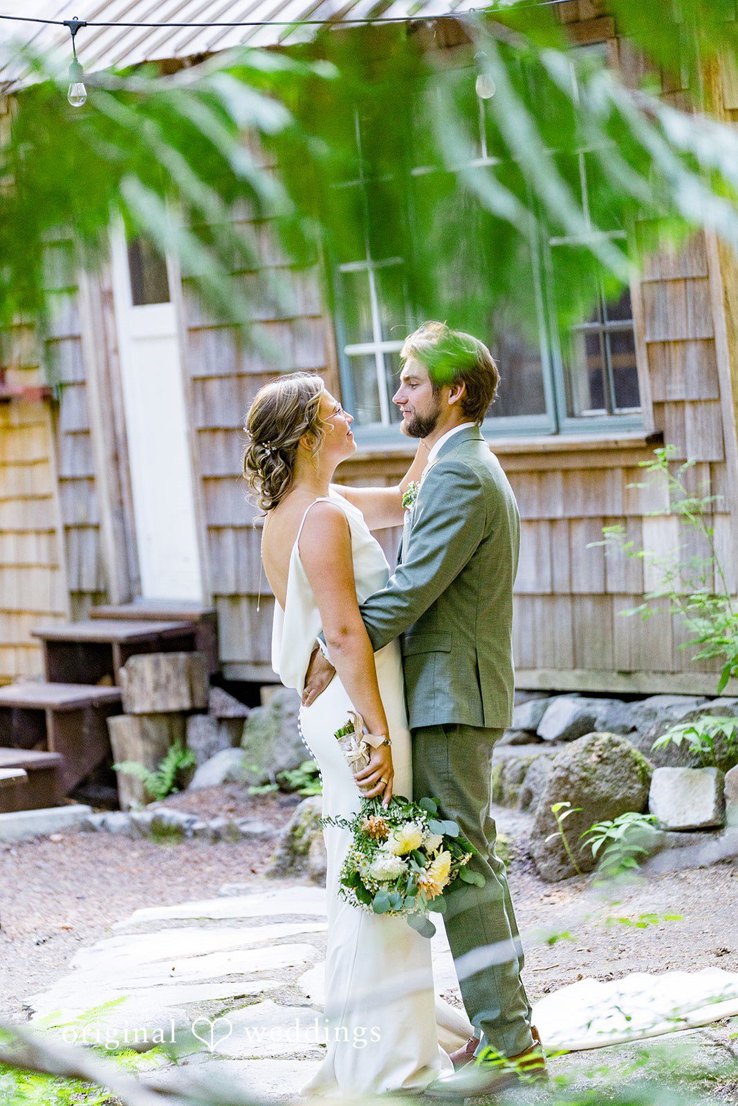 Abigail + Reece A bride and groom standing near a rustic cabin.