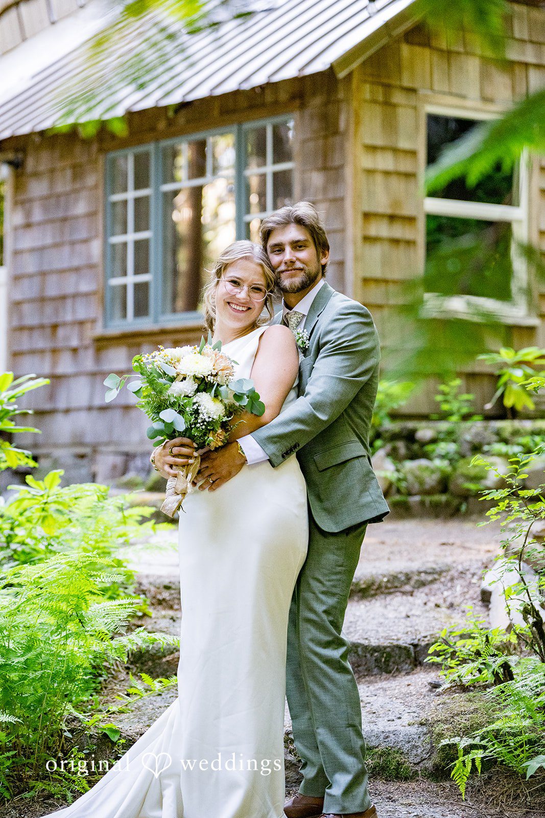 Abigail + Reece A bride and groom embracing in front of a wooden building.