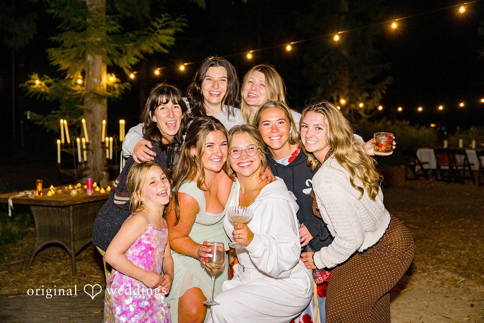 Abigail + Reece A group of wedding guests posing tightly together at a nighttime reception.
