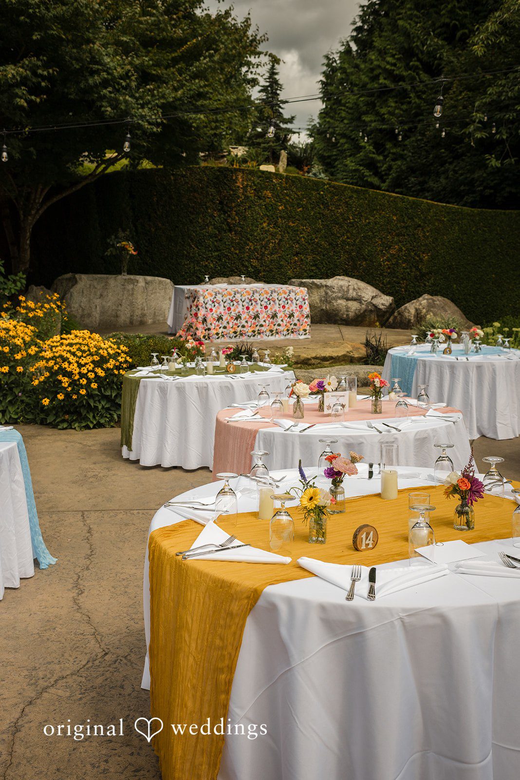 Diego + Adel Round reception tables set up on a patio, featuring bright yellow and white tablecloths.