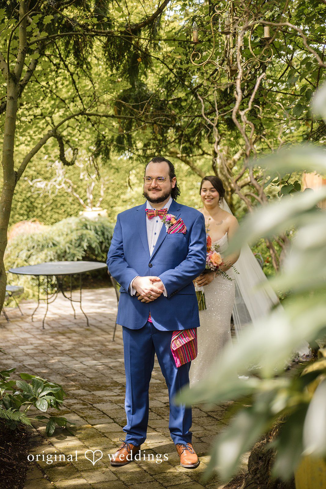 Diego + Adel A bride and groom walking together along a tree-lined path.