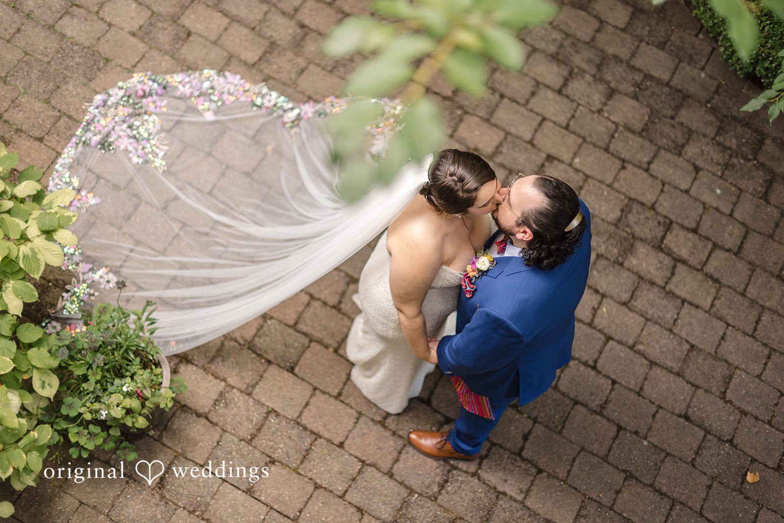 Diego + Adel An overhead view of a bride and groom embracing on a paved path.