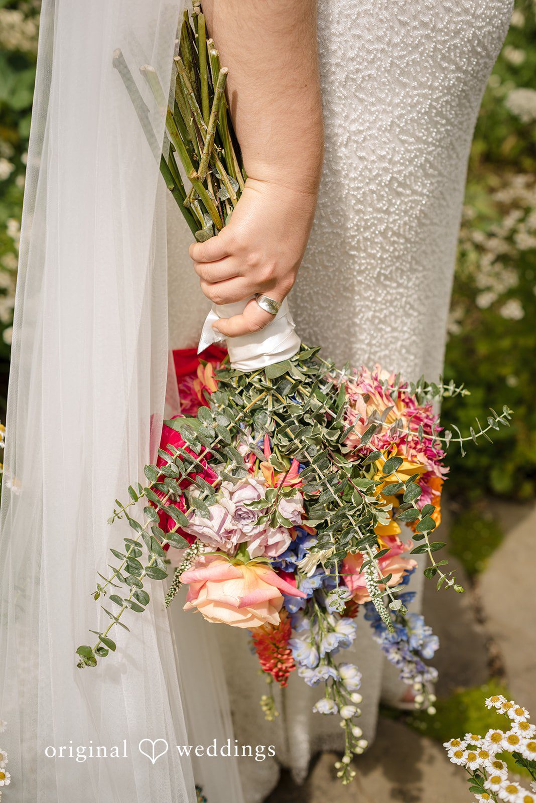 Diego + Adel A bride holding a vibrant, colorful floral bouquet against her white dress.