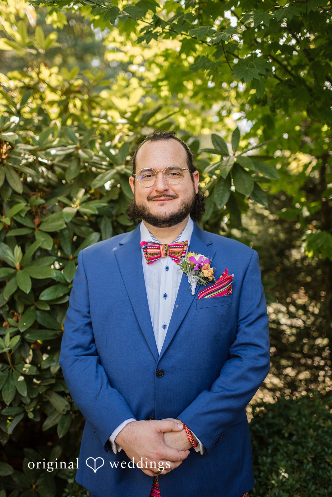 Diego + Adel A groom wearing a bright blue suit and a red bow tie smiling for a portrait.