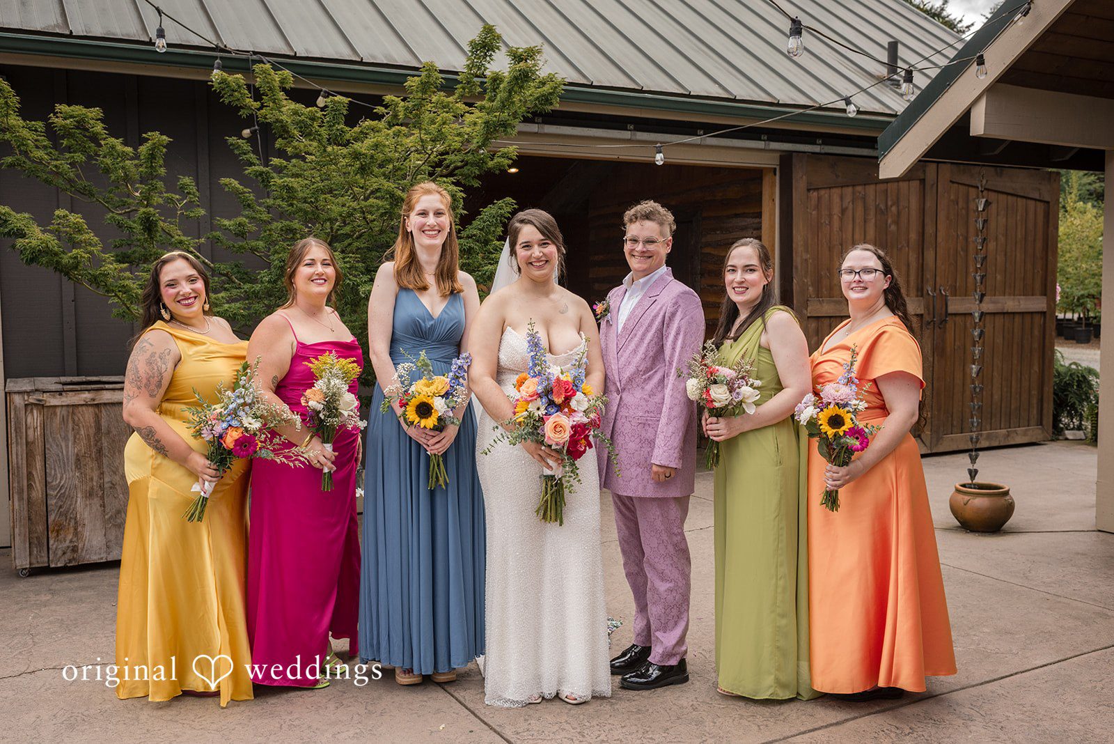 Diego + Adel A lineup of bridesmaids wearing mismatched, brightly colored dresses standing side-by-side.