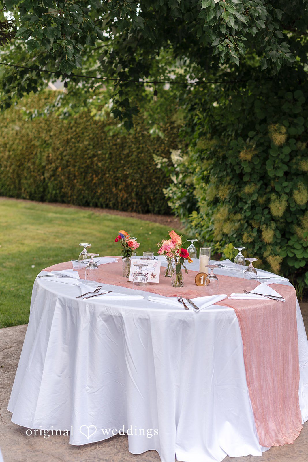 Diego + Adel A wedding reception table dressed with a white tablecloth and a pink fabric runner.