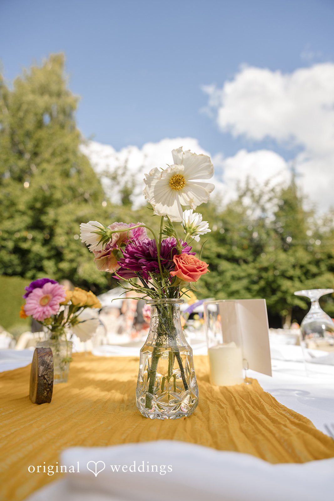 Diego + Adel A wedding table setting displaying a yellow runner and a colorful floral centerpiece.