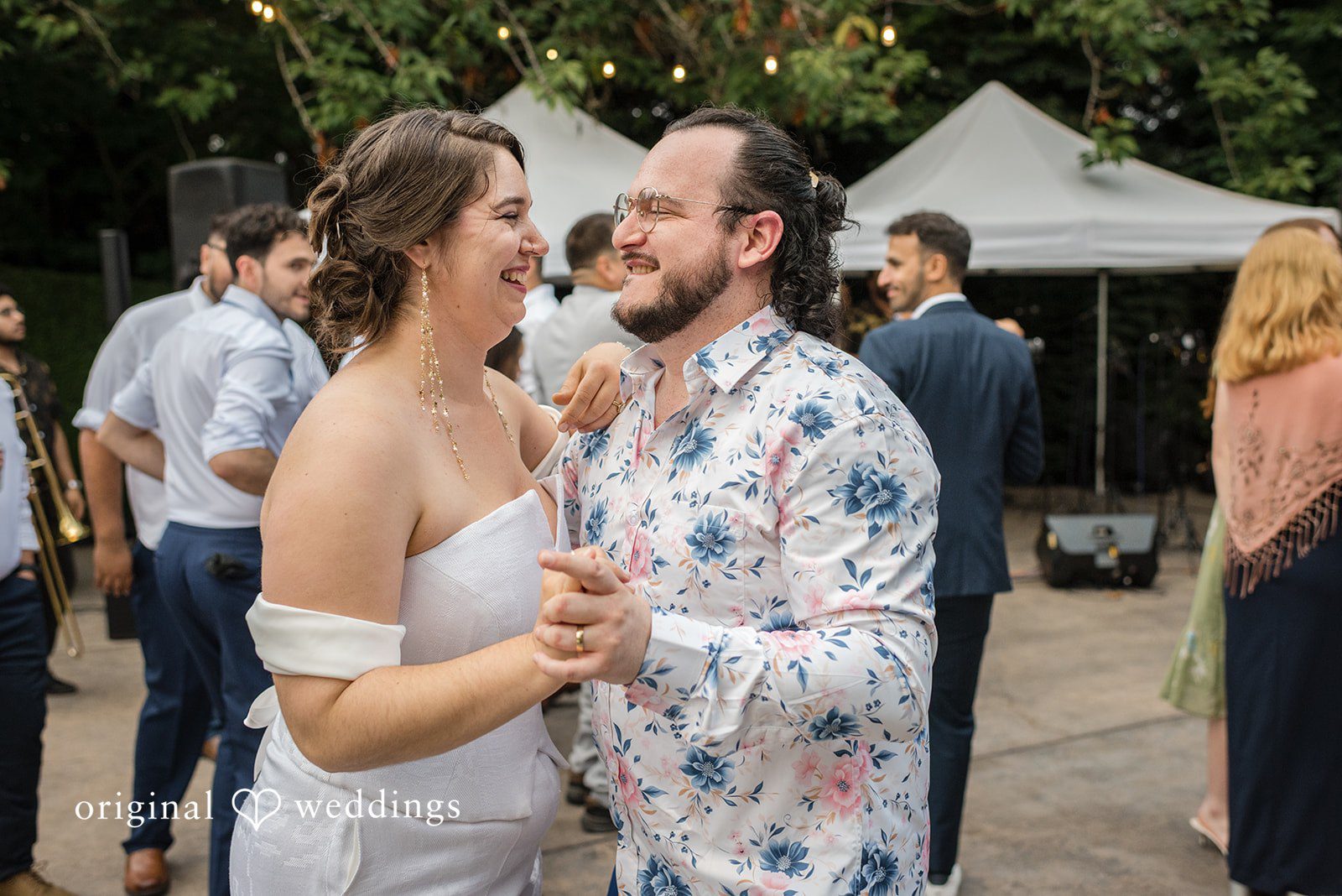 Diego + Adel A groom in a patterned shirt dancing with his bride at the reception.