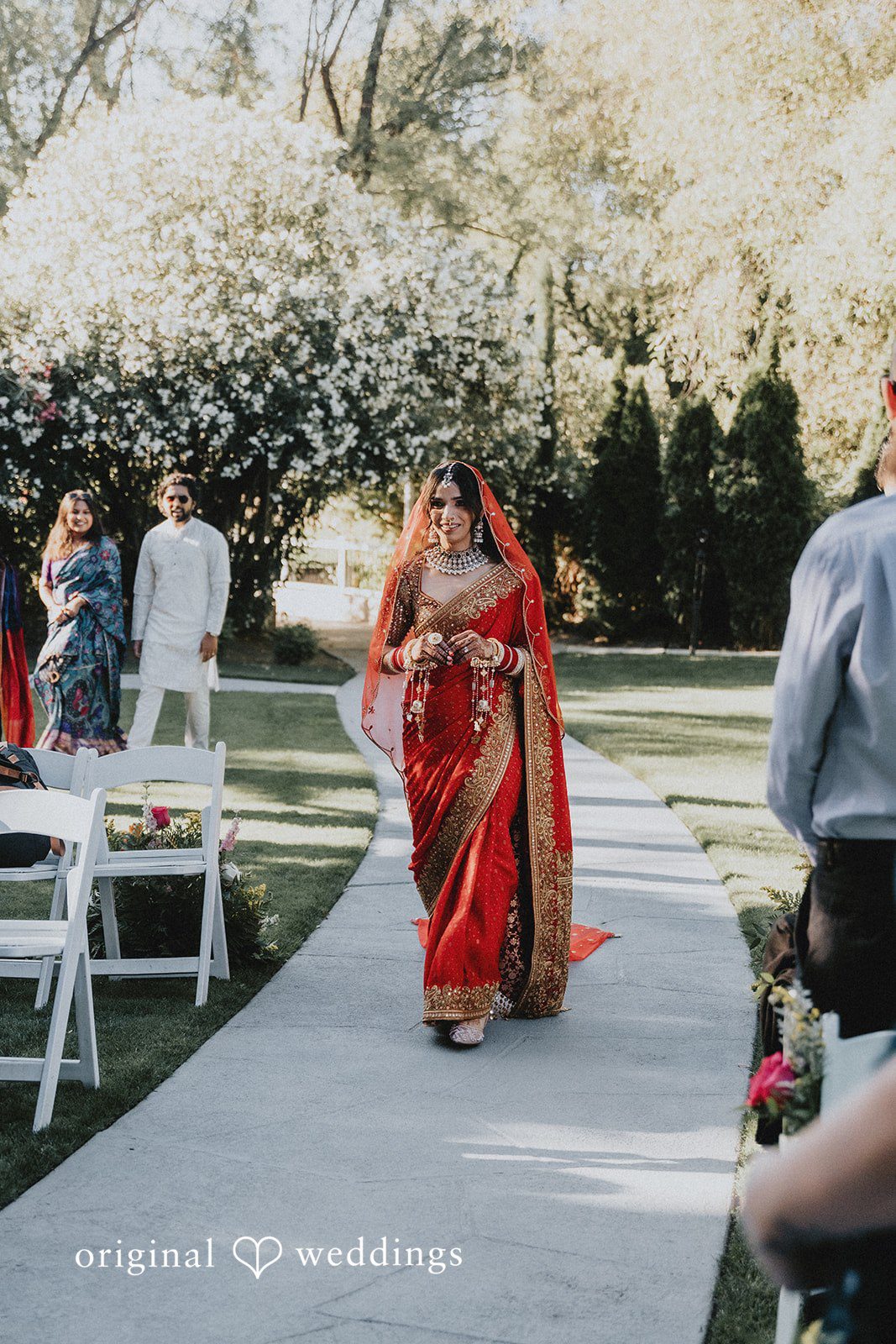 A bride in a red dress walking down an aisle.