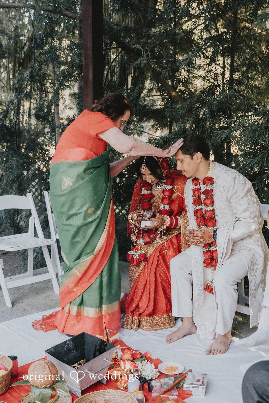 A women performing a traditional wedding ritual over a seated bride.