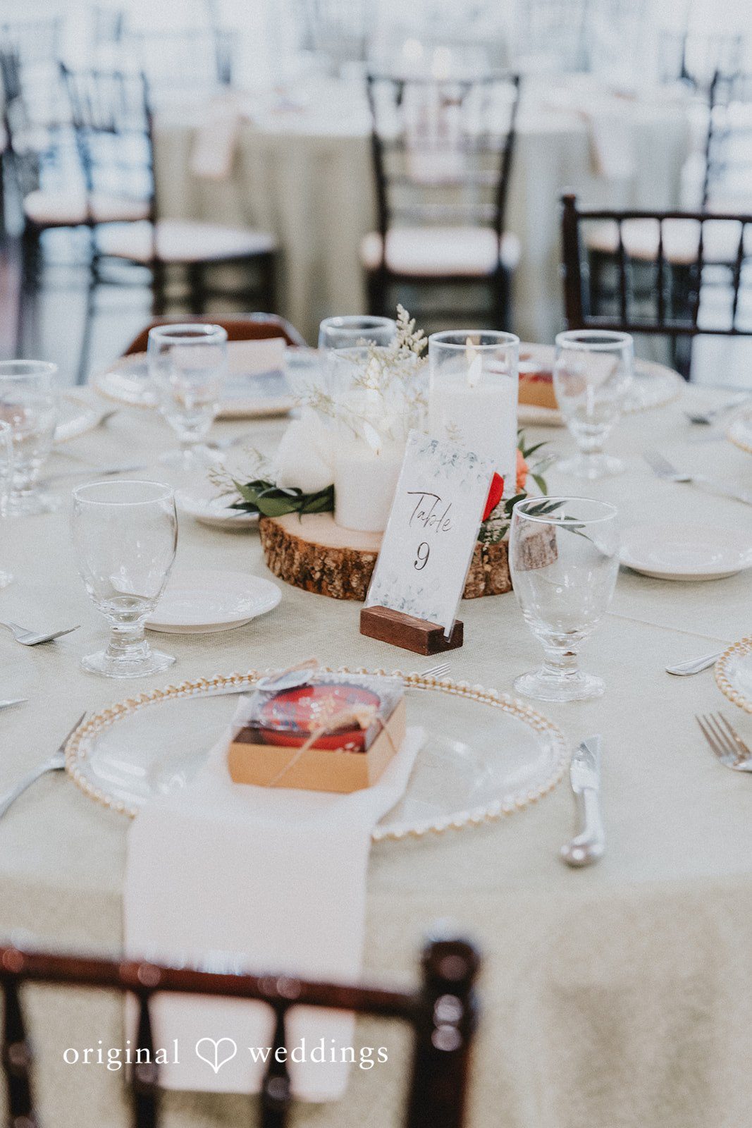 A long wedding reception table set with white linens, plates, and glassware.