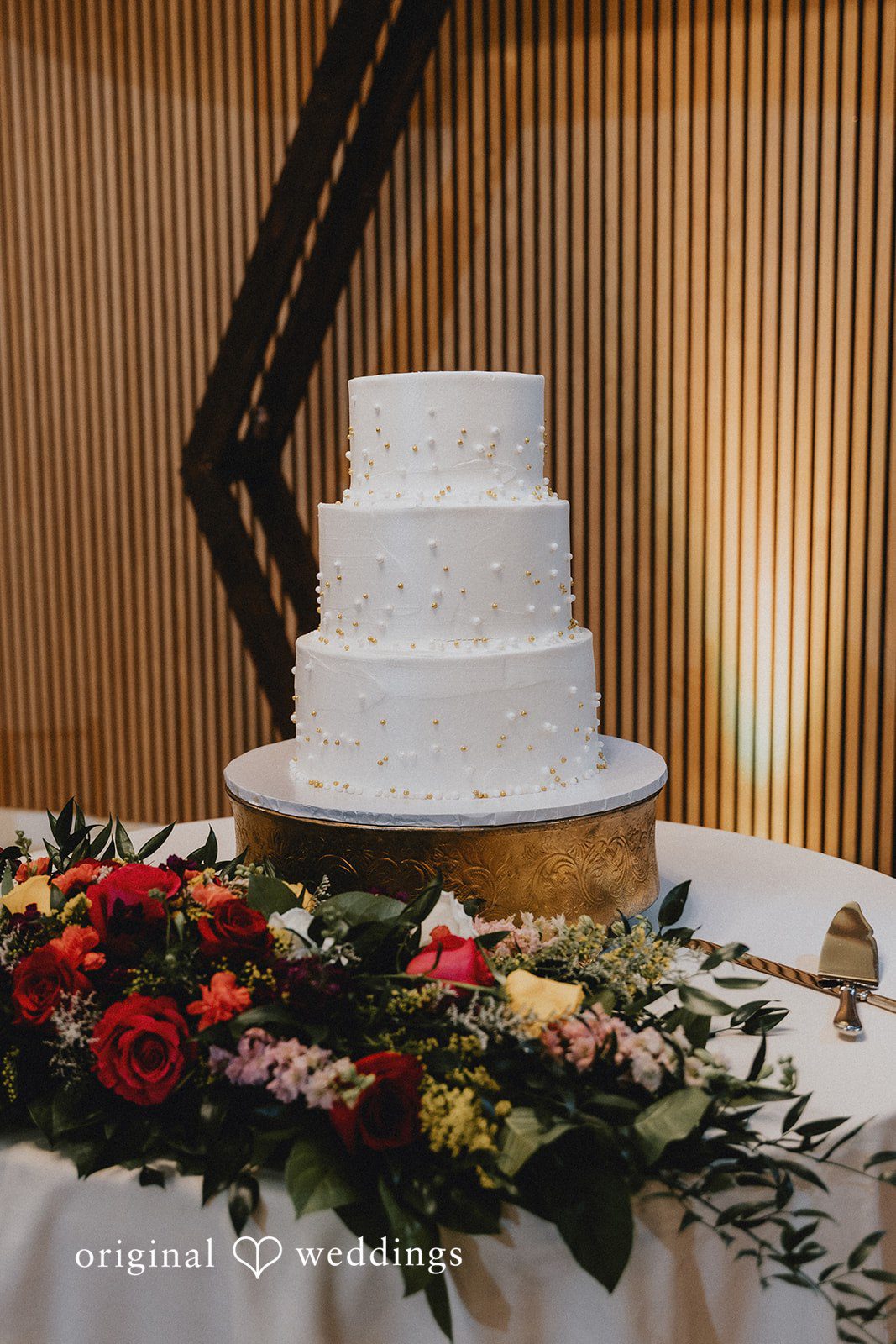 A multi-tiered white wedding cake decorated with fresh flowers on a table.