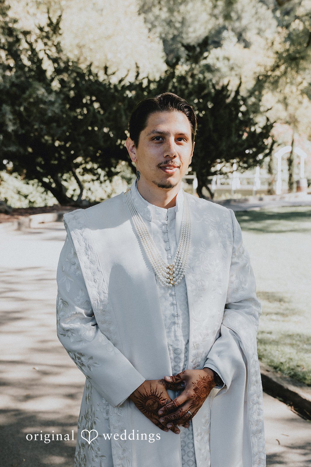 A groom standing in a traditional white sherwani.