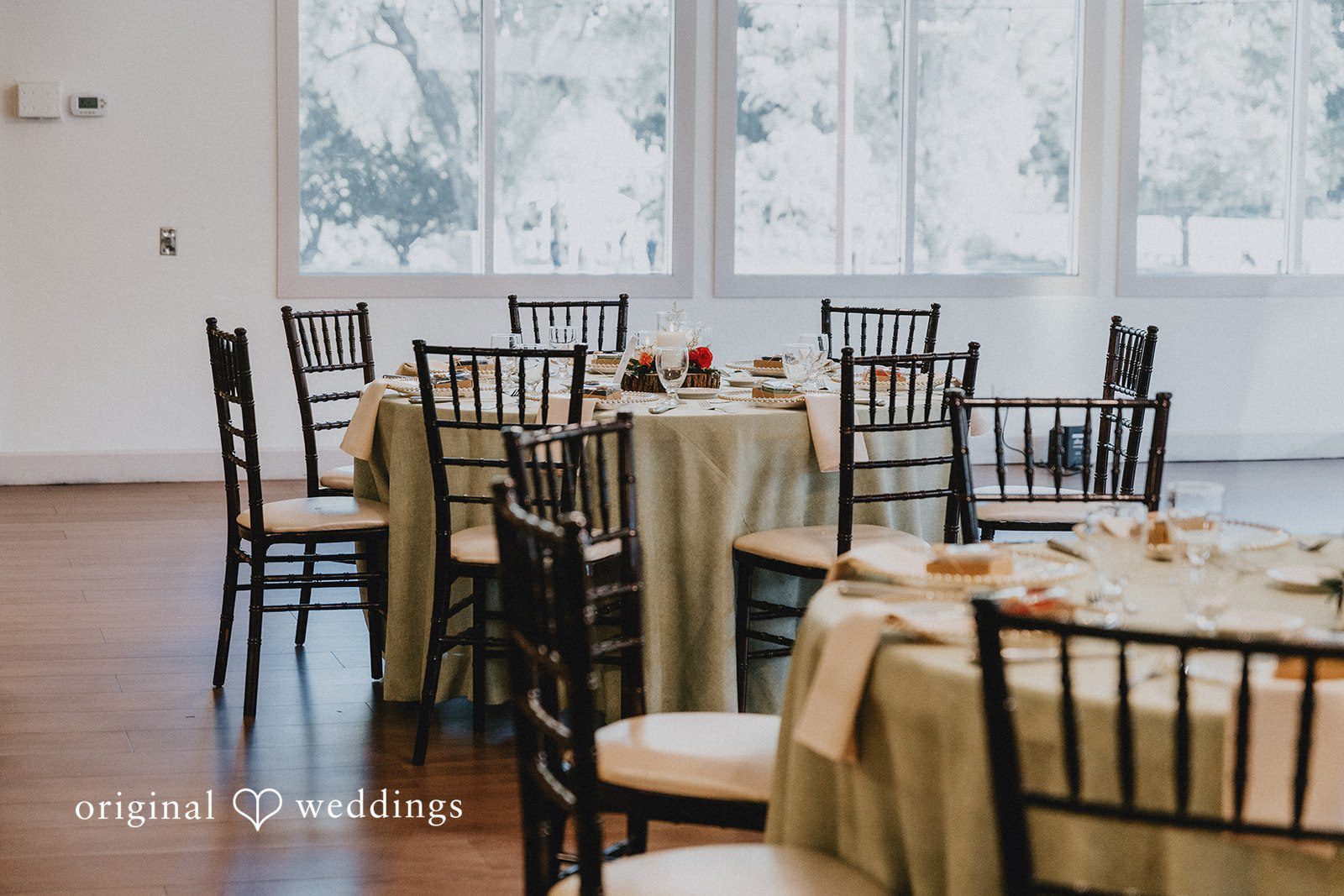 An empty reception room featuring round dining tables and dark chairs.