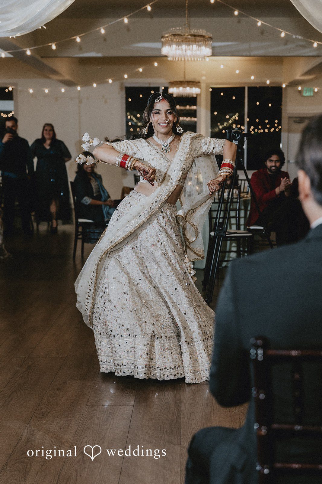 A bride spinning in a white lehenga while performing a dance routine.