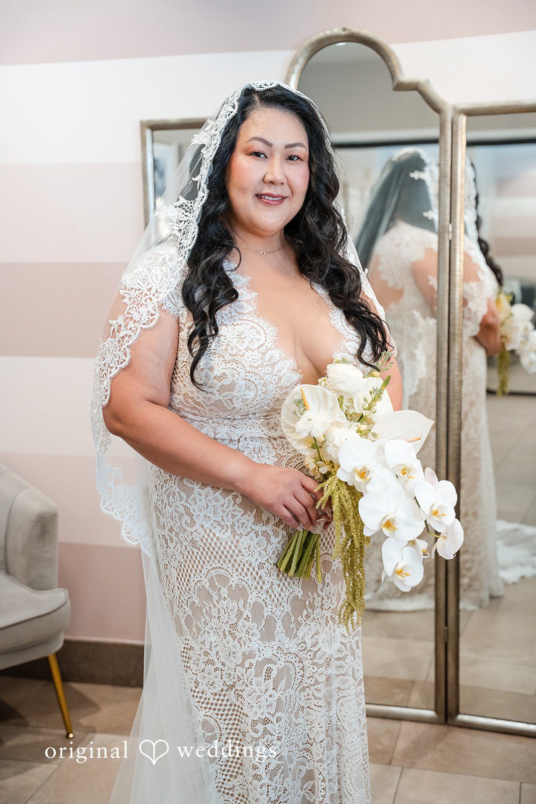 A bride holding a white bouquet while posing in front of a window.