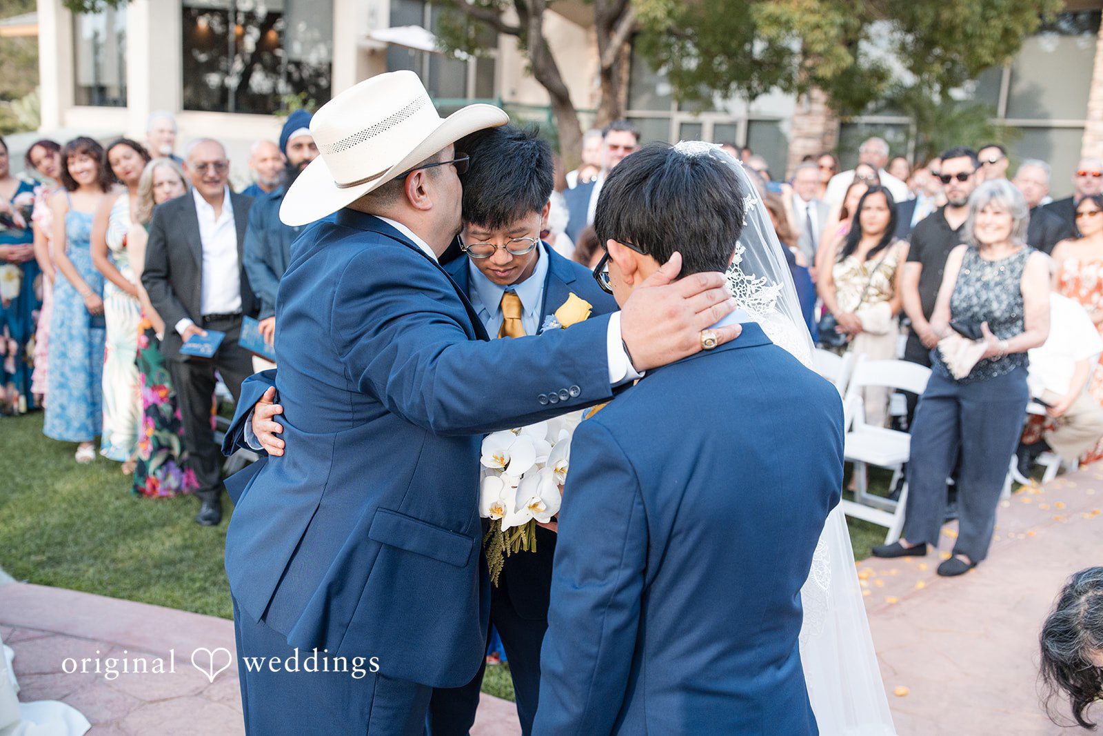 A groom having his suit jacket adjusted before the ceremony.