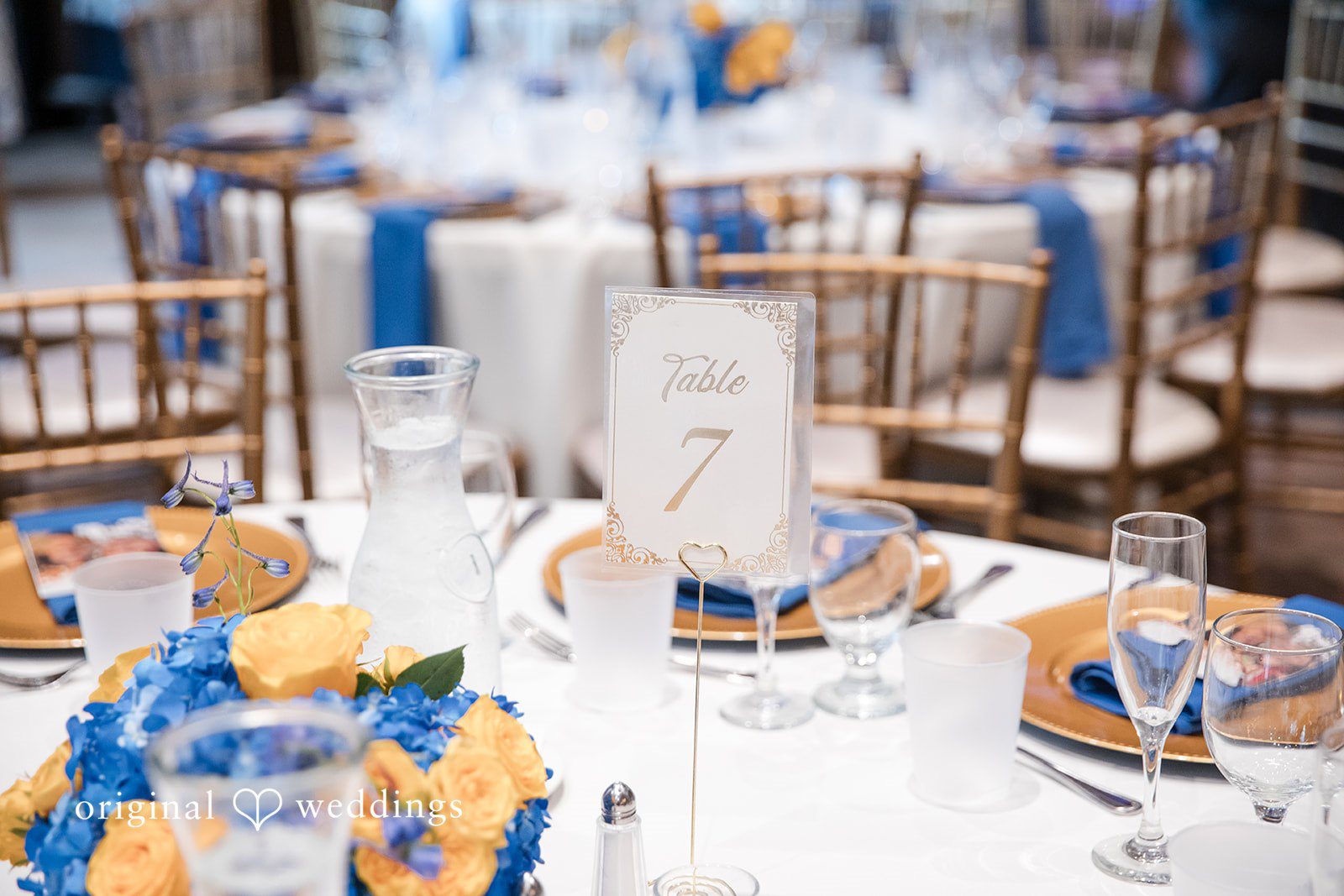 A long reception table arranged with white floral centerpieces.