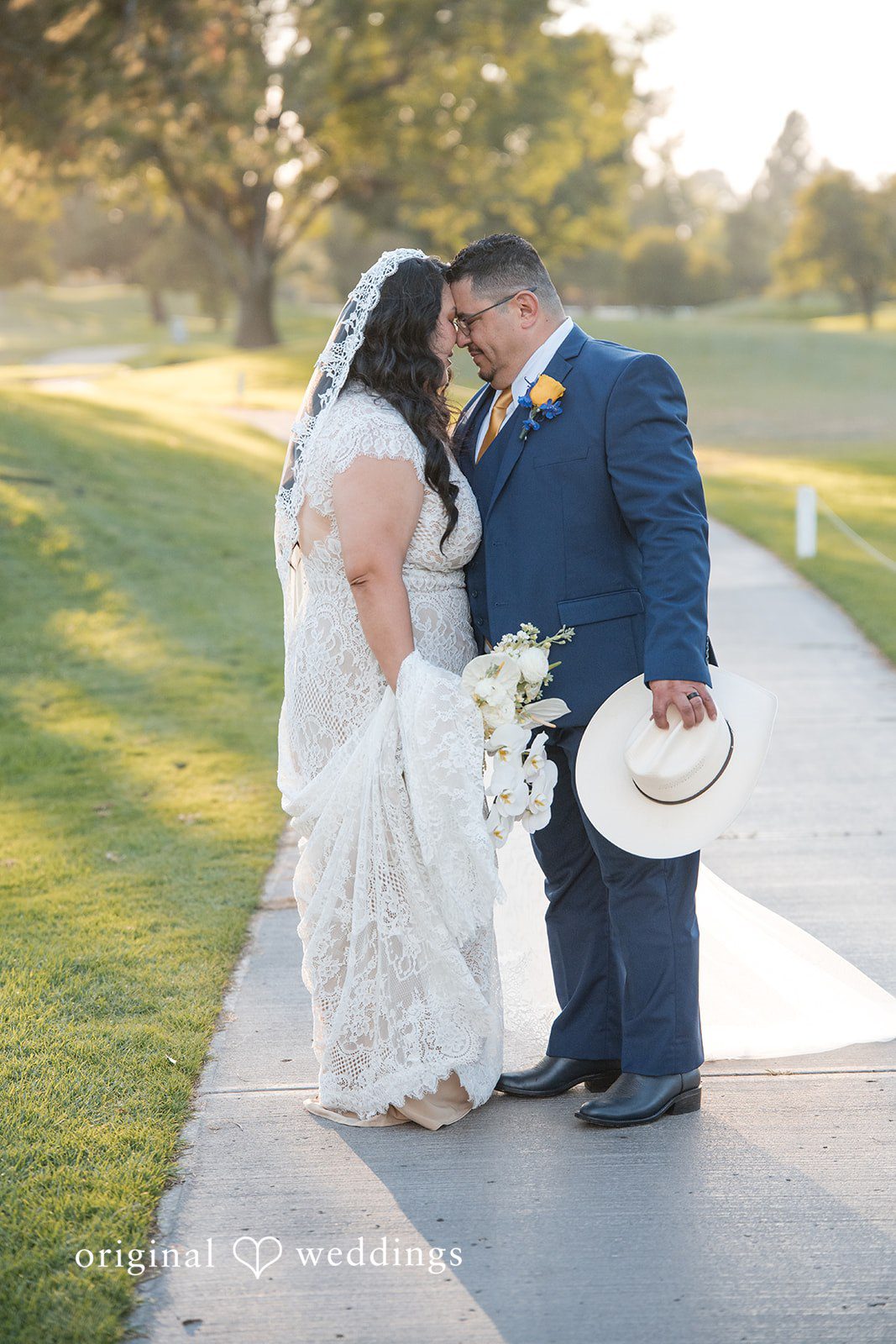 A bride and groom walking hand-in-hand along a paved pathway.