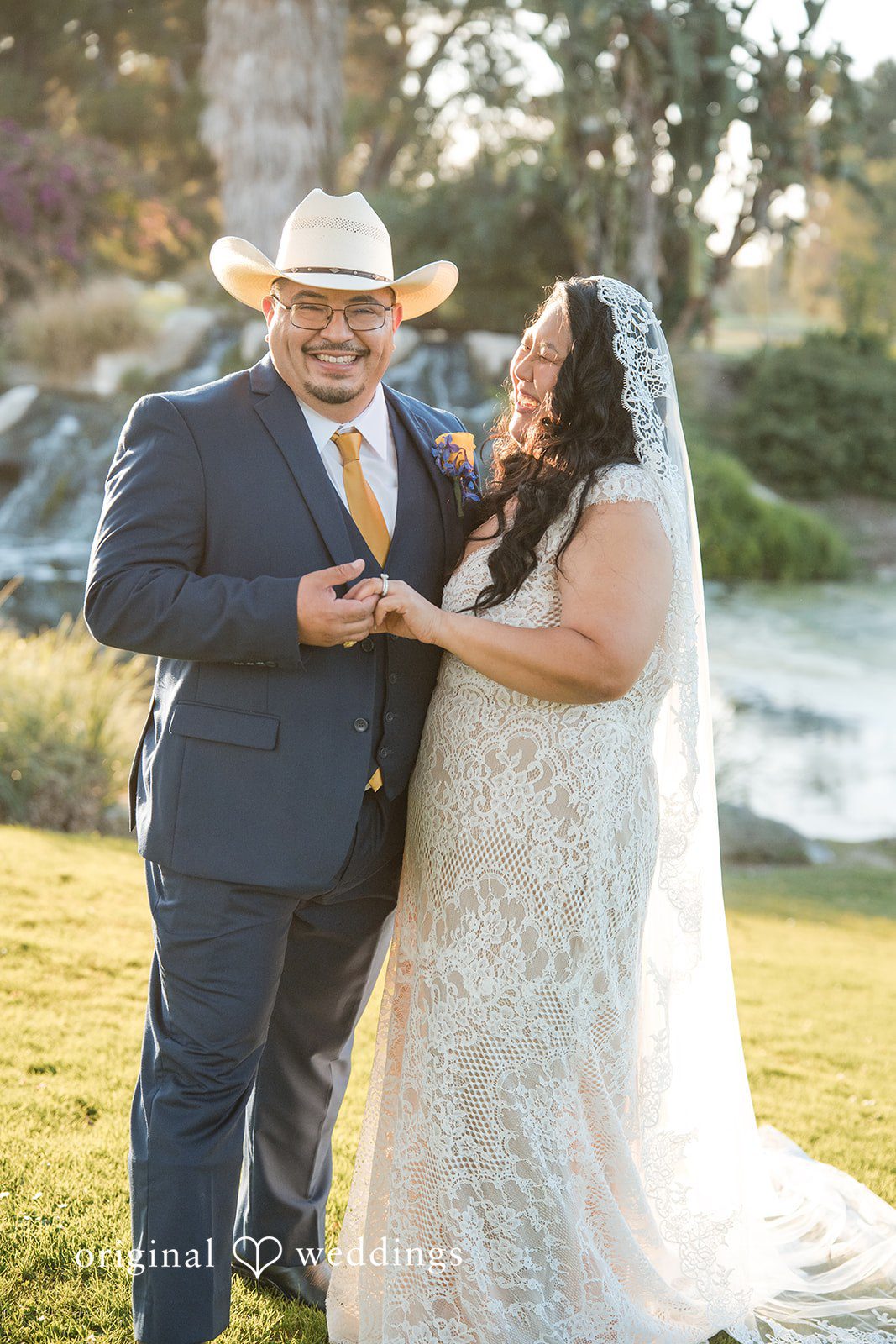 A bride and groom holding hands and smiling at each other.