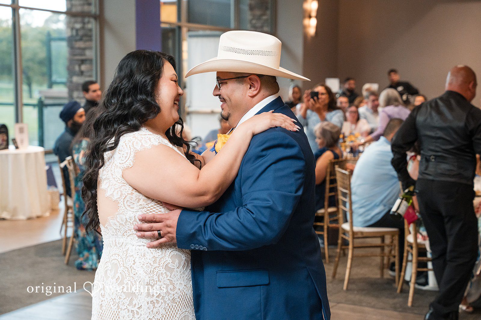 A bride and groom sharing a slow dance surrounded by their guests.
