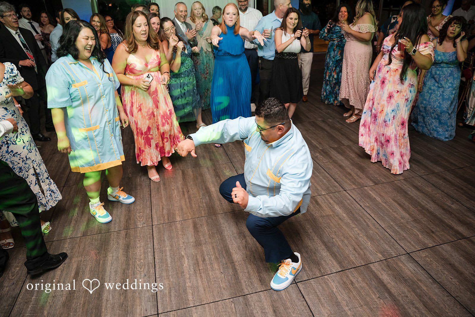 A groom doing a dance move low to the ground on the floor