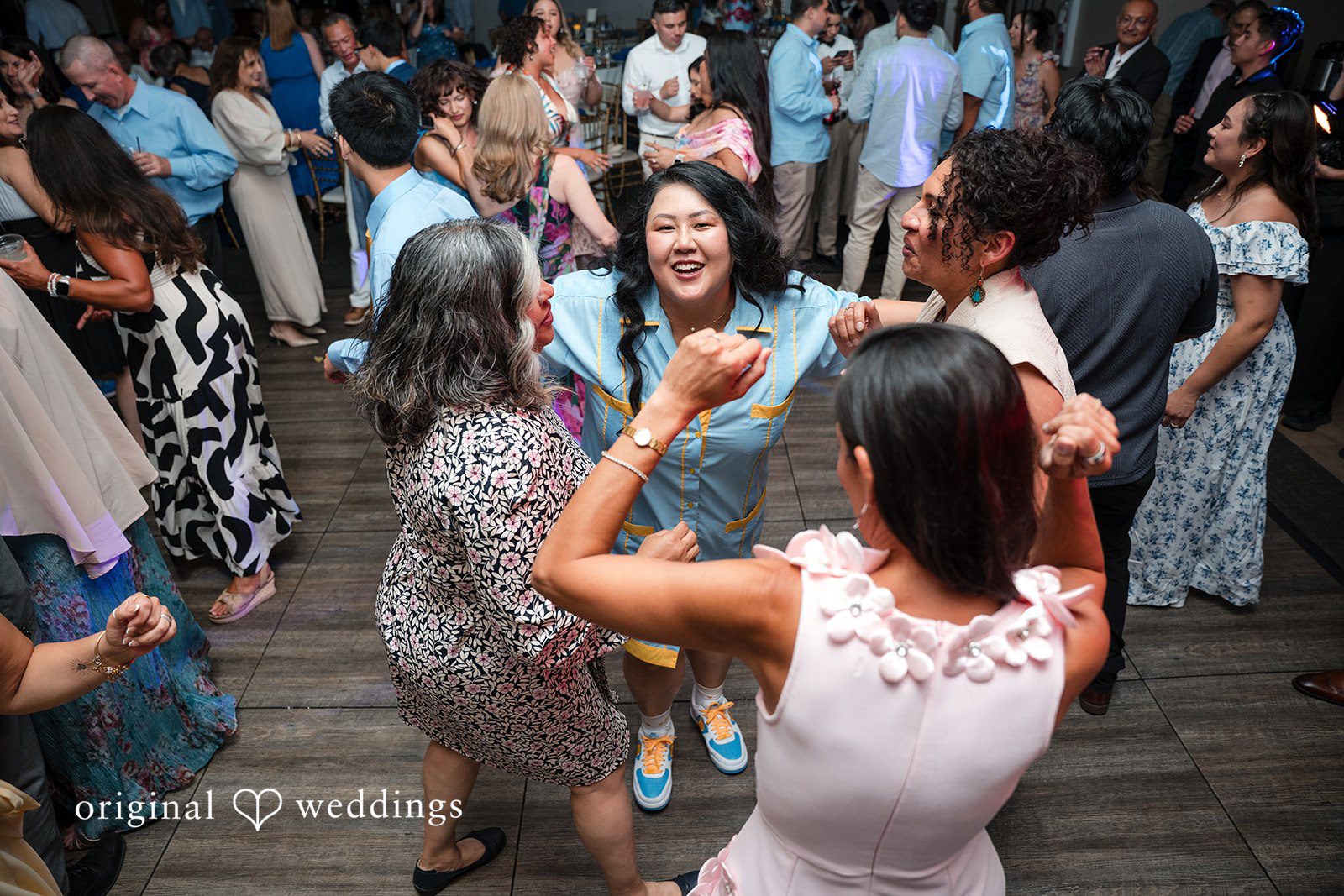 Wedding guests dancing energetically together on a crowded dance floor.
