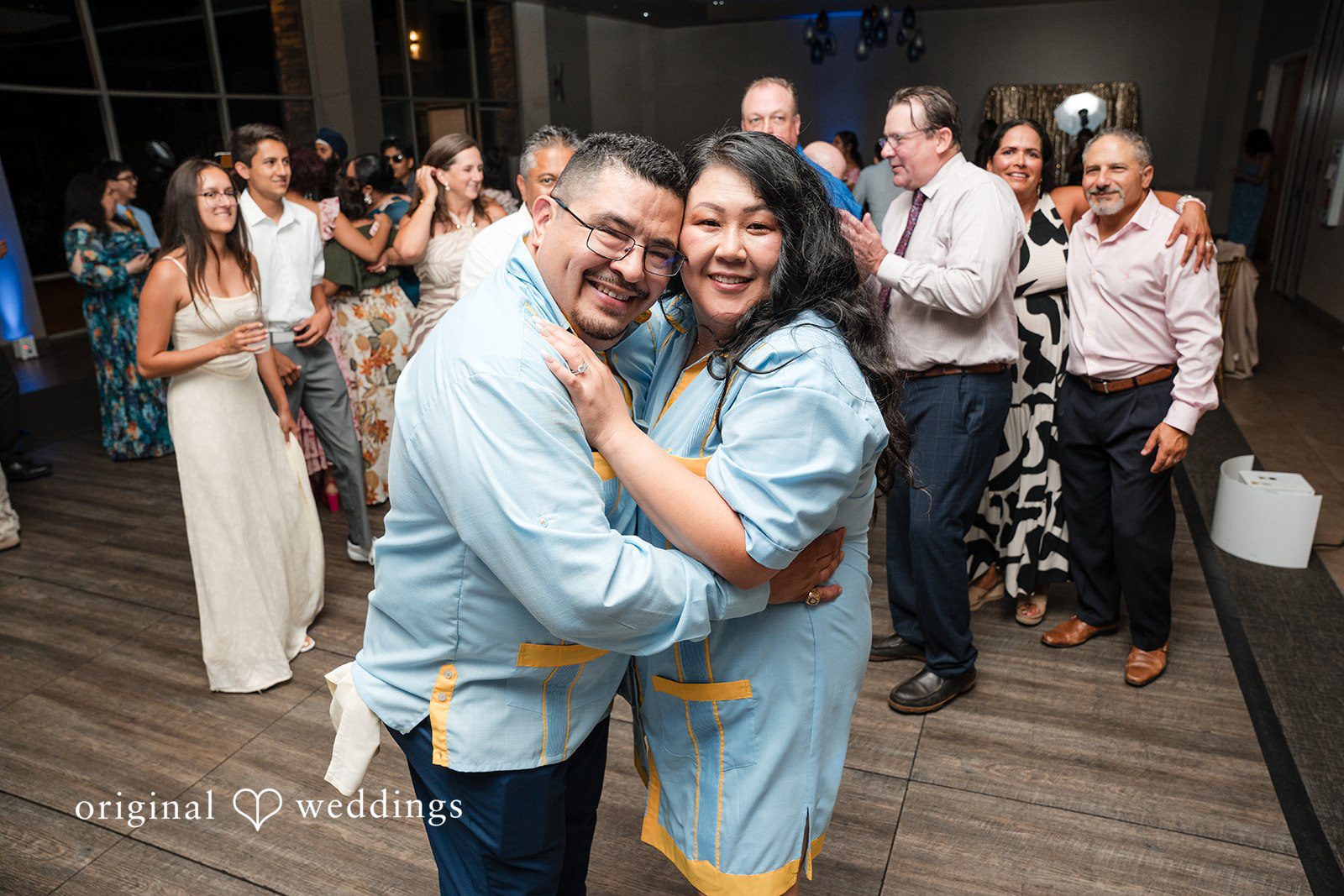 A couple smiling and embracing tightly on a packed dance floor.