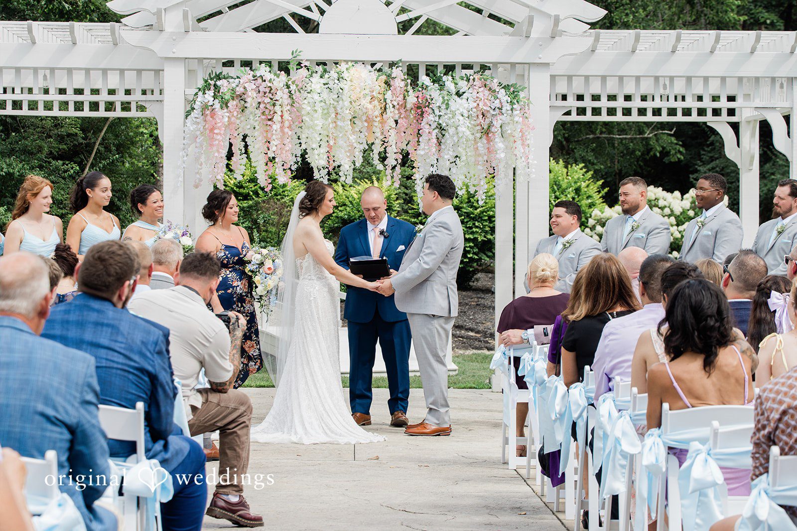Alexander + Annalisse Couple and wedding party members stand assembled at the ceremony altar area.