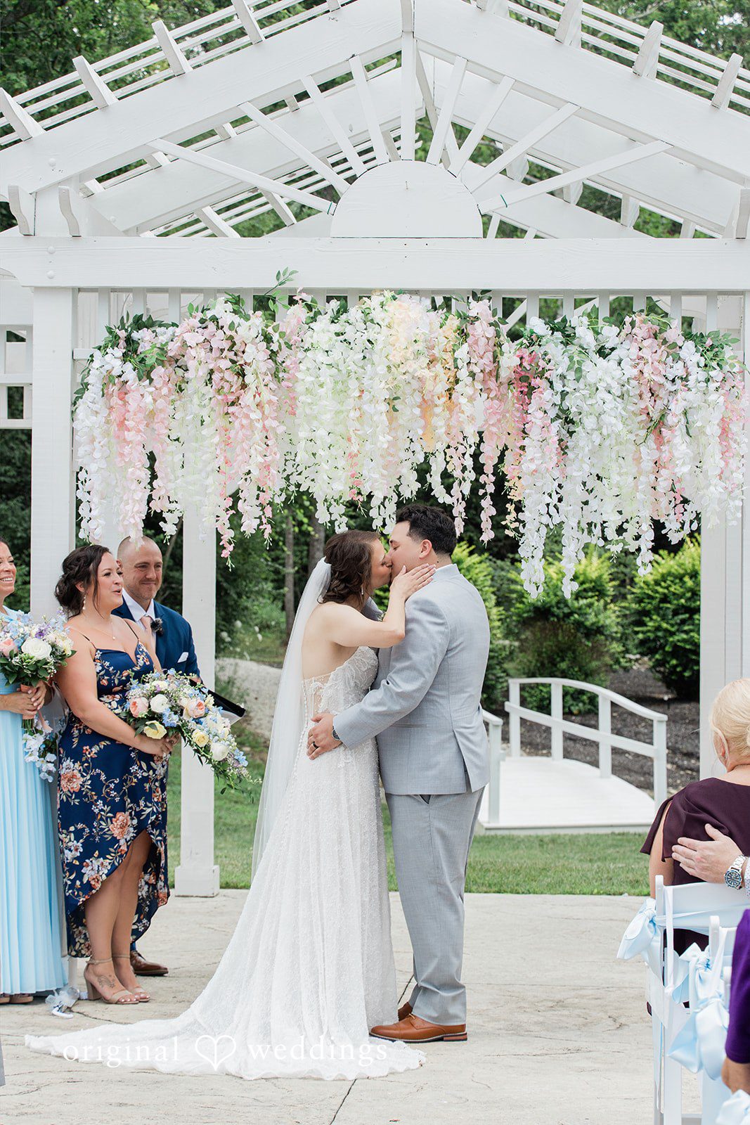 Alexander + Annalisse A bride and groom share a romantic embrace under a white ceremonial pergola.