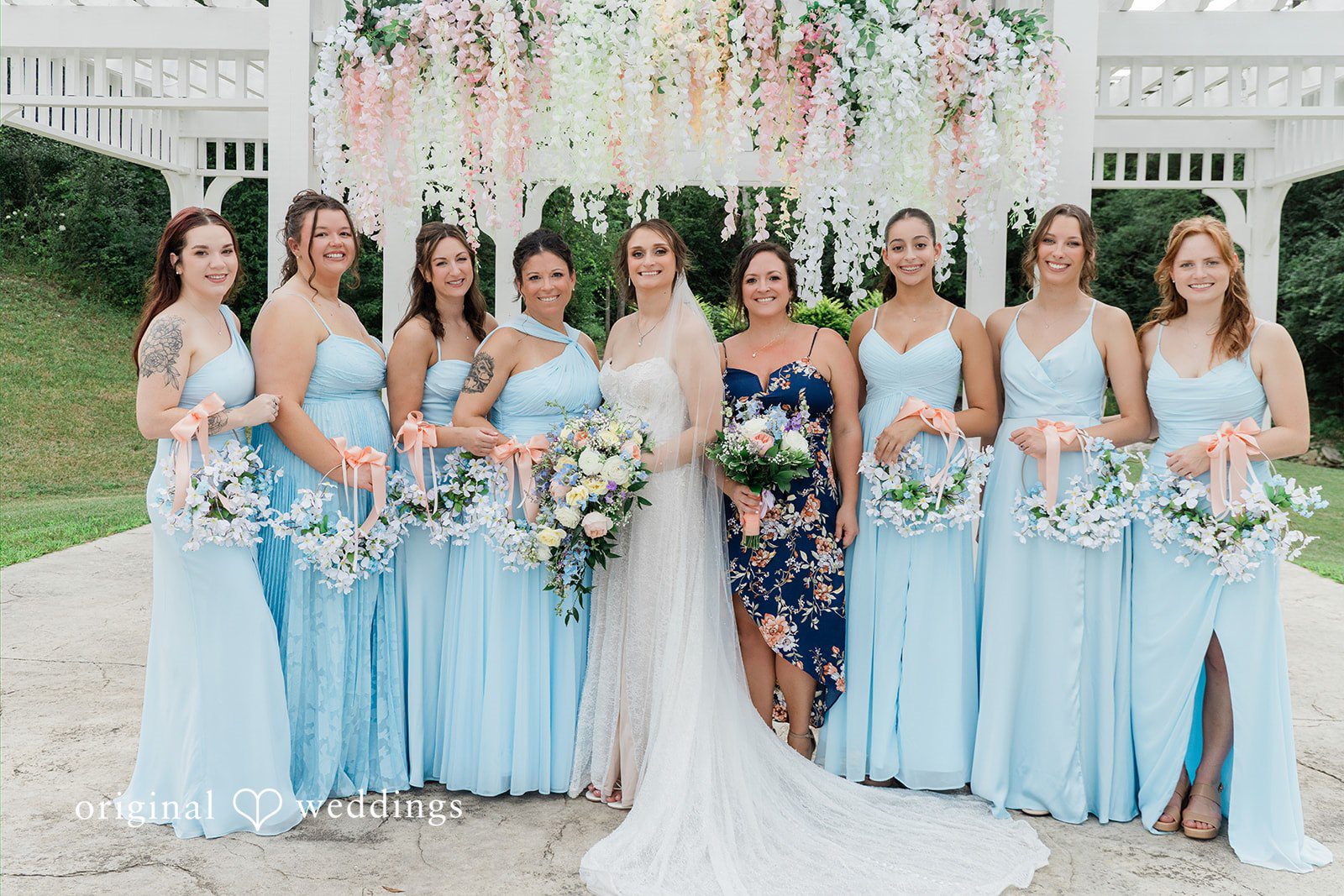 Alexander + Annalisse A bride and her bridesmaids in matching light blue dresses pose together for a group portrait.