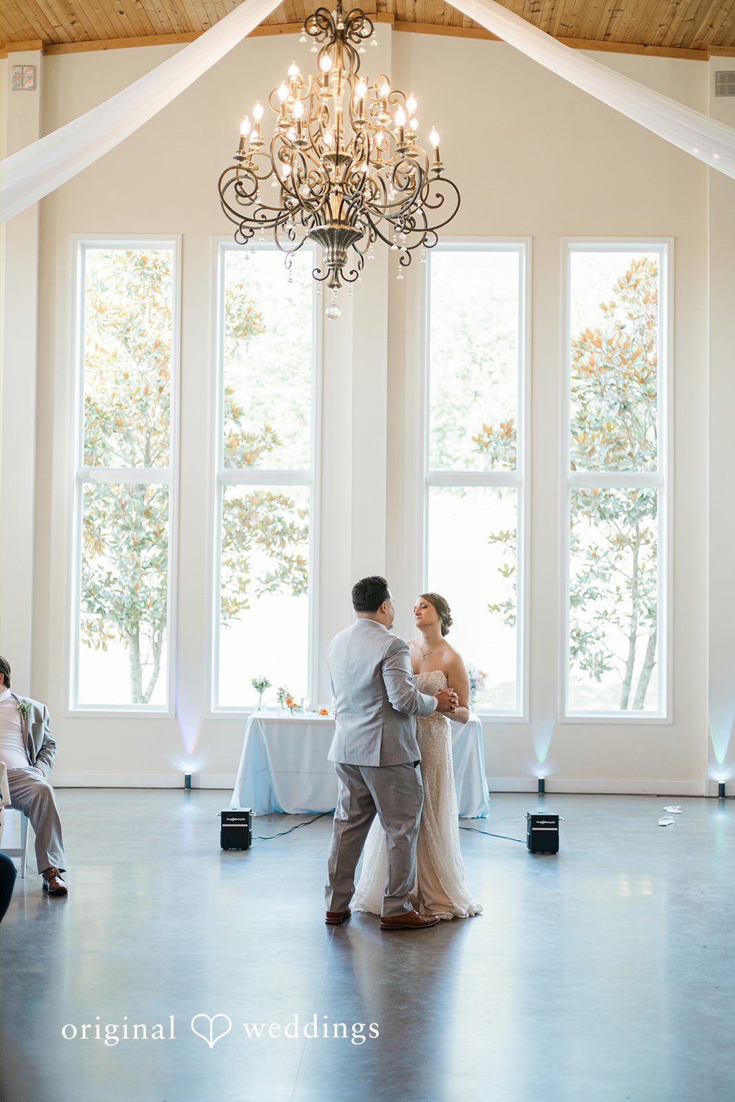 Alexander + Annalisse A wide view of a spacious reception hall with large windows as people dance on the floor.