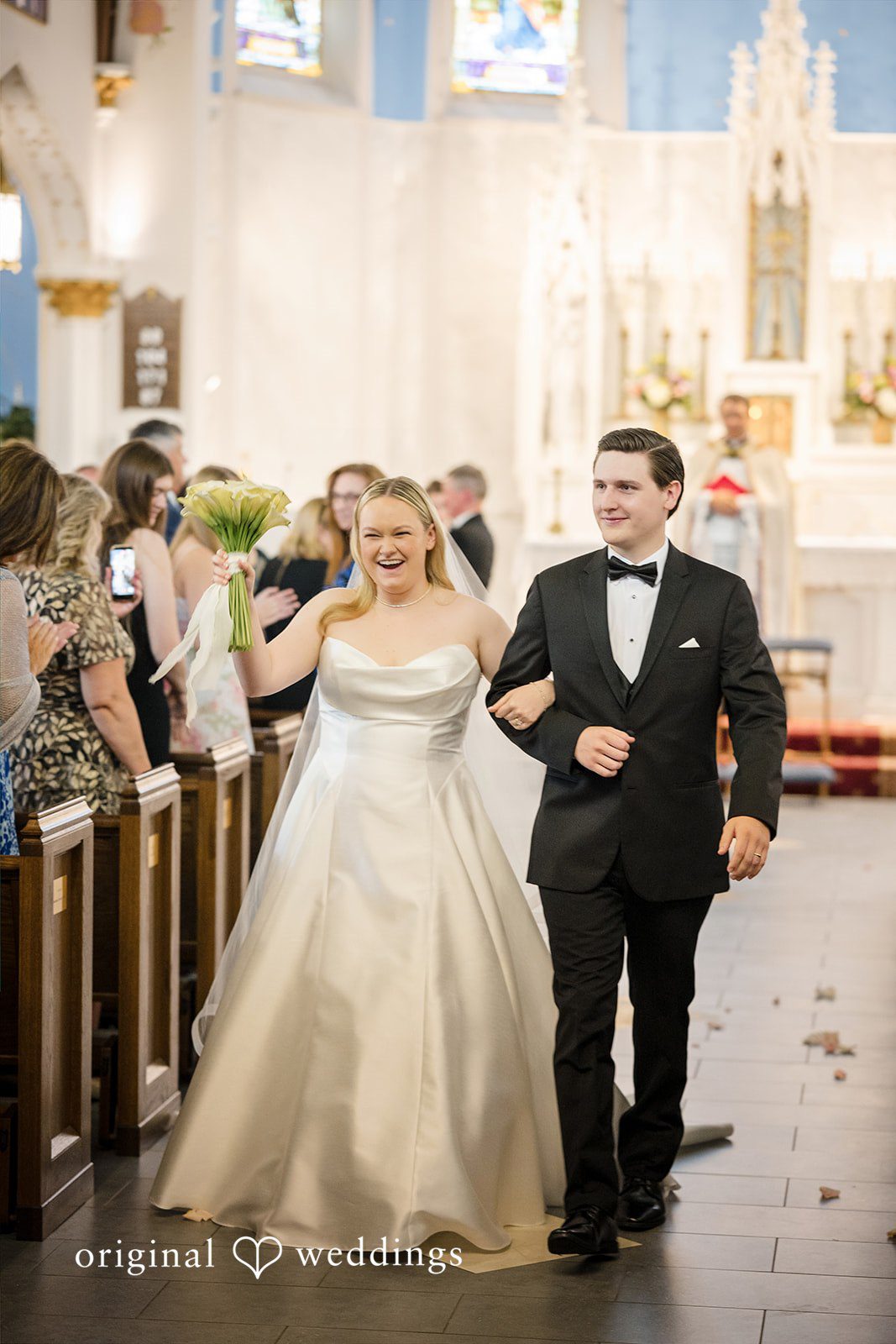 Nicole + Matt A newlywed bride and groom smiling as they walk down the aisle together.