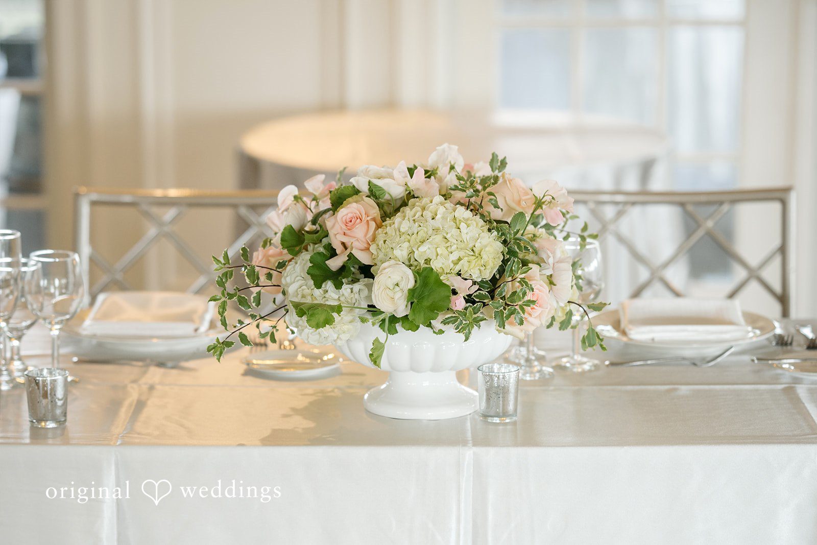 Nicole + Matt A decorated wedding reception head table with white floral arrangements and glassware.