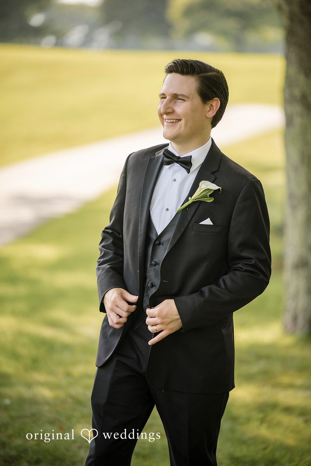 Nicole + Matt A groom in a black tuxedo posing in a grassy field.