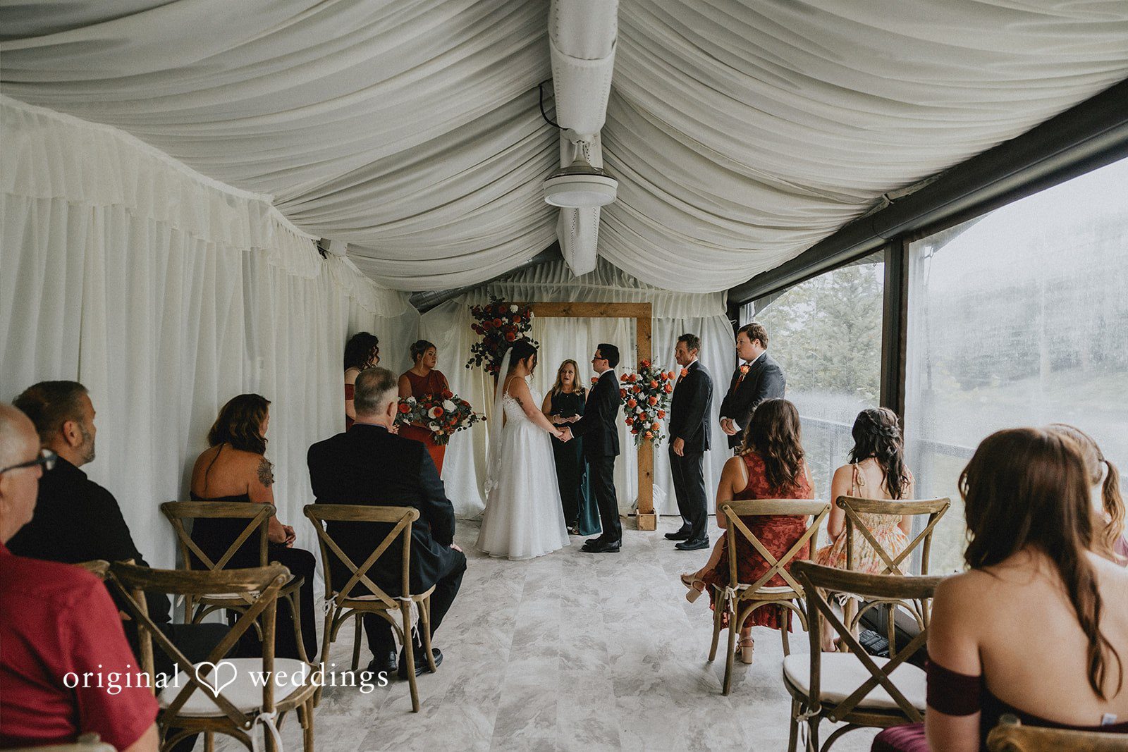Guests seated in rows during a wedding ceremony inside a tent structure.