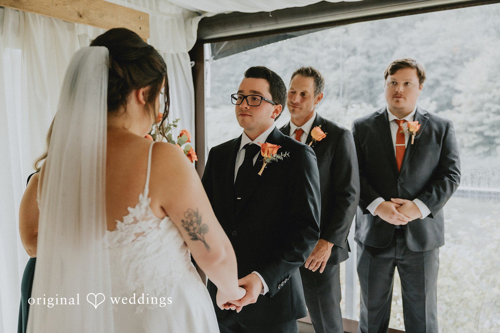 A bride and groom standing before a rustic wooden arch during a ceremony.