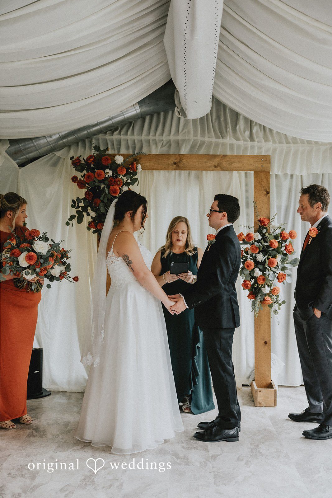 A wide view of a wedding ceremony in progress inside a decorated venue.